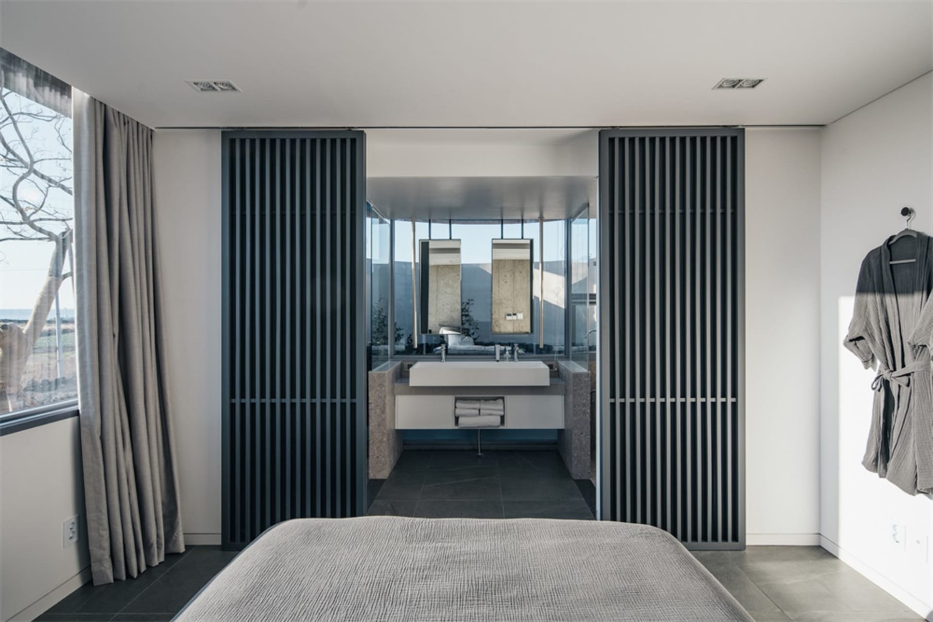A modern bedroom featuring concrete and glass materials.