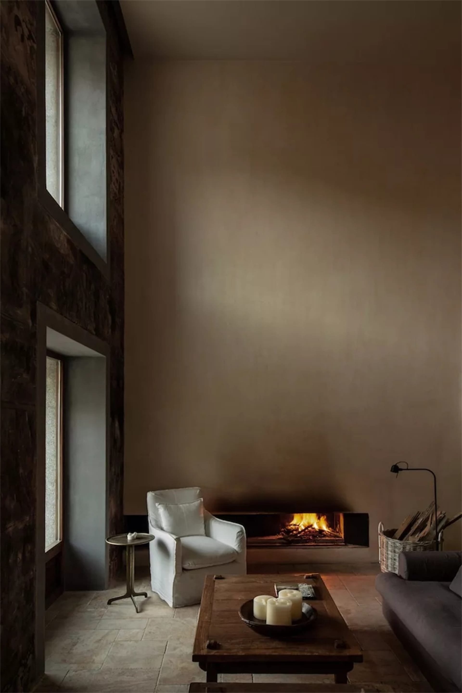 Minimalist living room featuring a stone, wood, and concrete design scheme with a fireplace, sofa, and coffee table.
