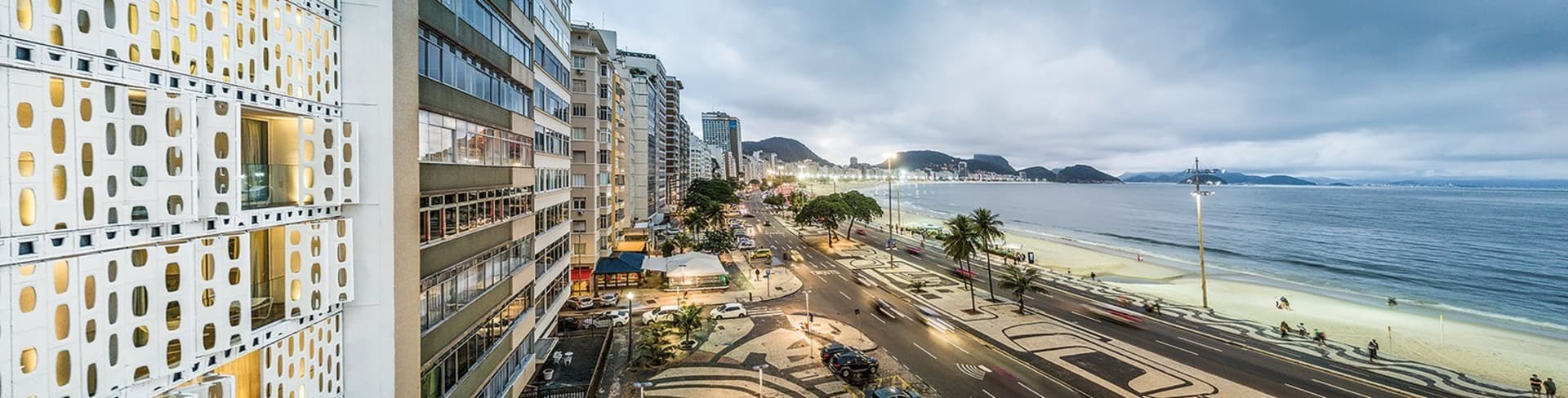 Modern concrete building by the beach with high-rise structures in the background