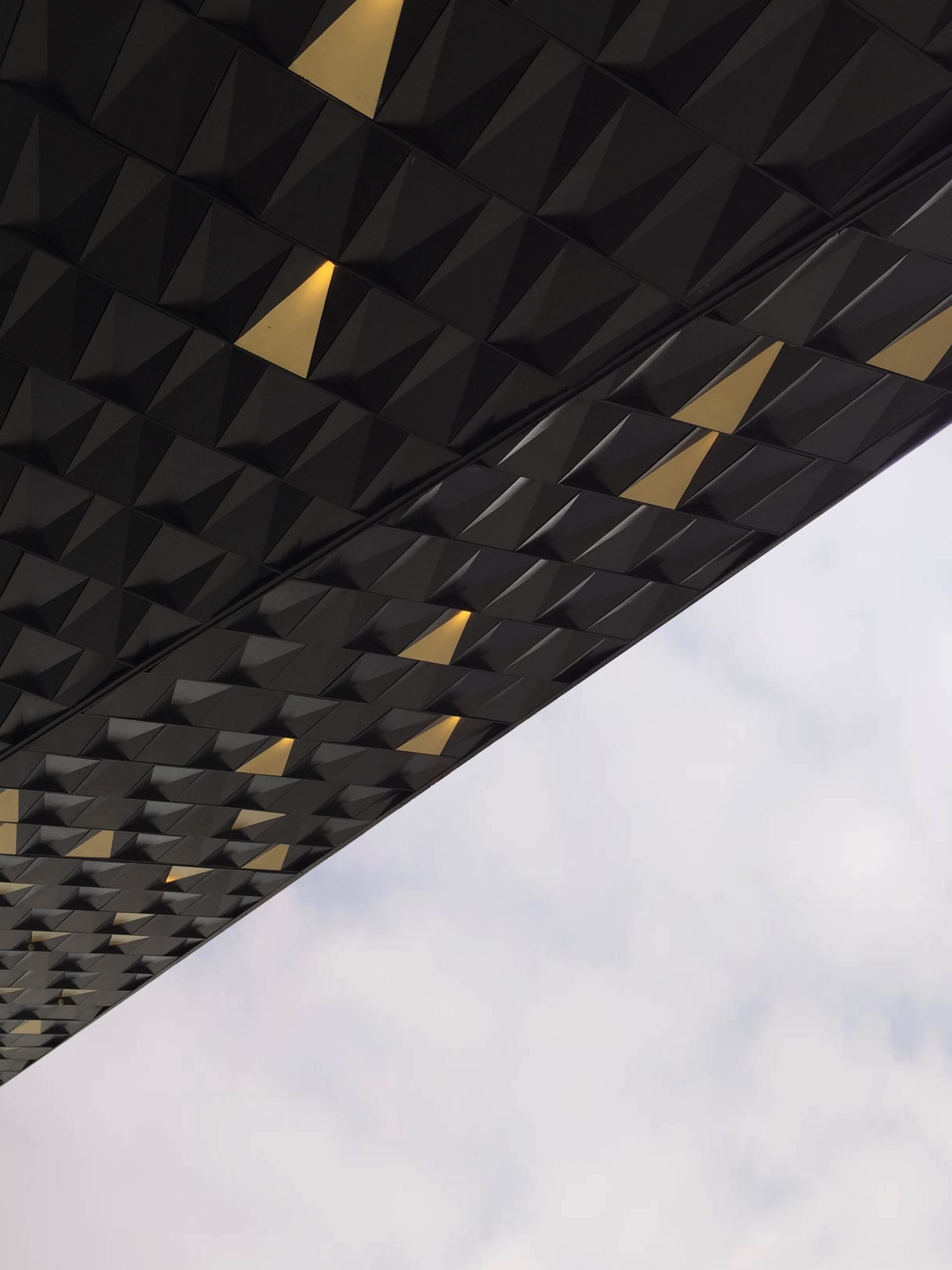 A modern ceiling with a metallic black texture and geometric patterns featuring yellow accents.