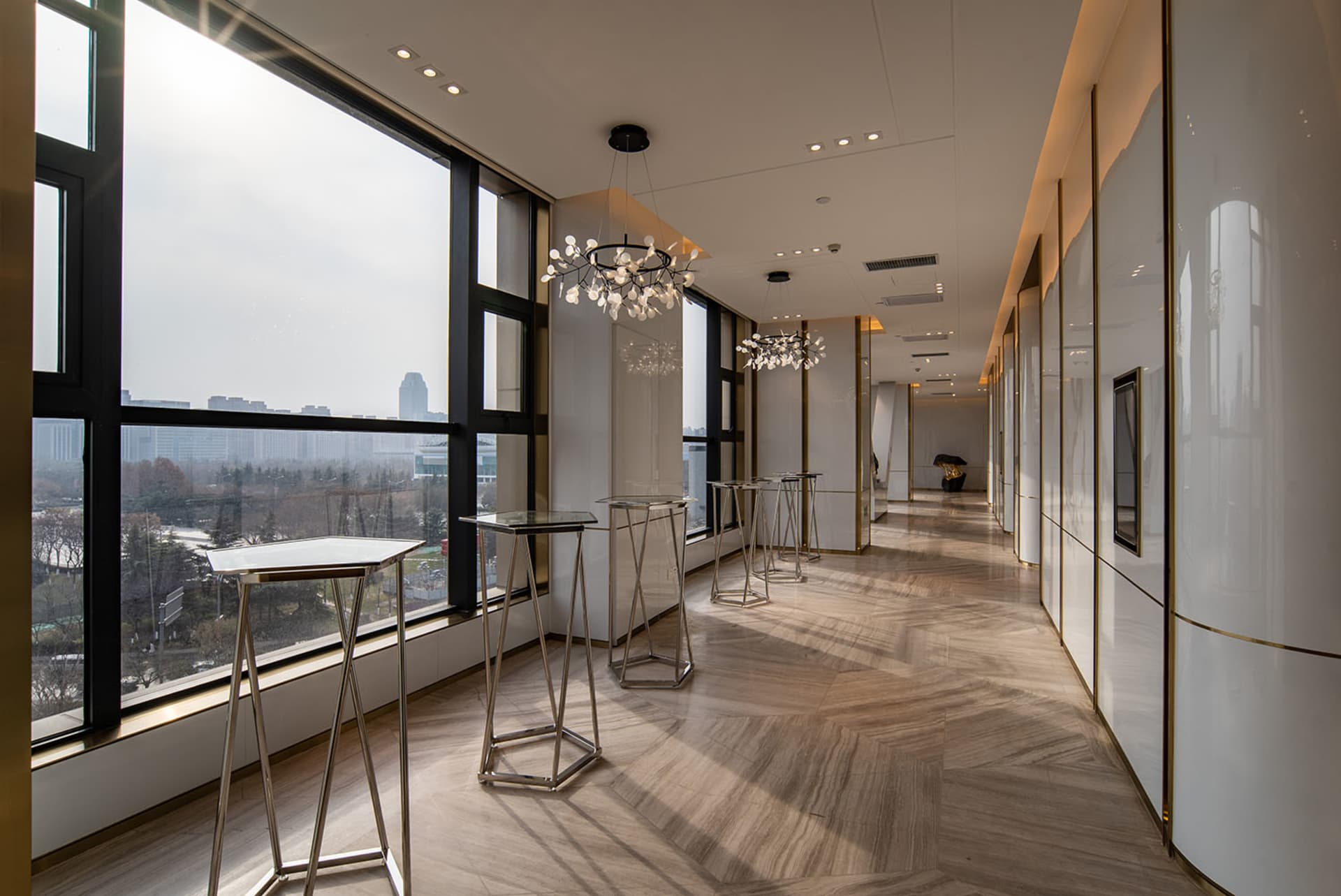 A modern corridor with glass walls, metal railings, and marble flooring.