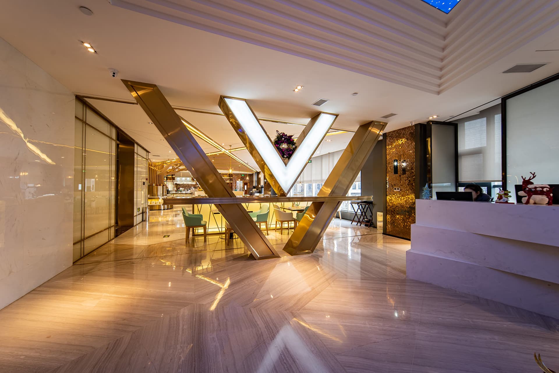 Modern hotel reception area with marble flooring, glass walls, and metal accents.