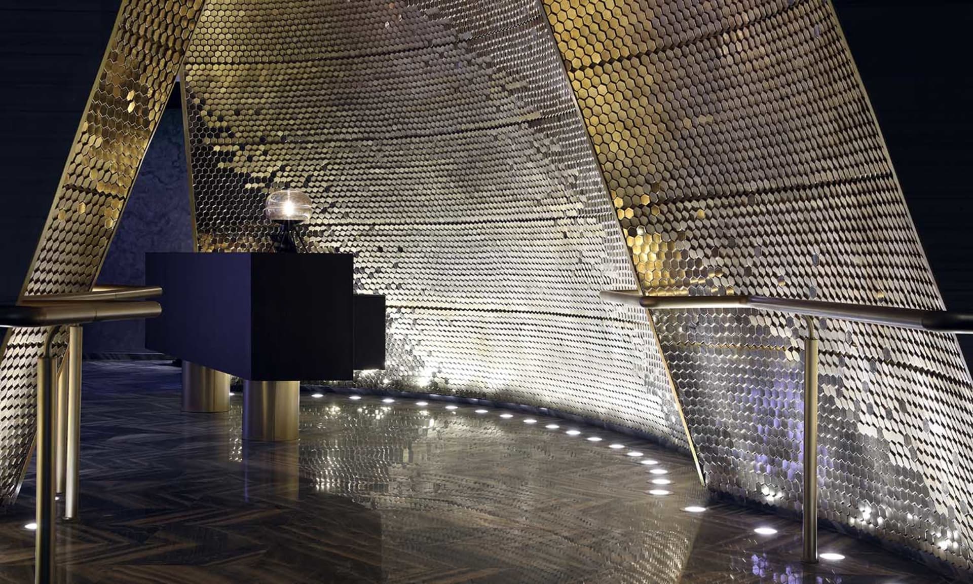 A modern lobby featuring a metallic hexagonal-patterned ceiling.