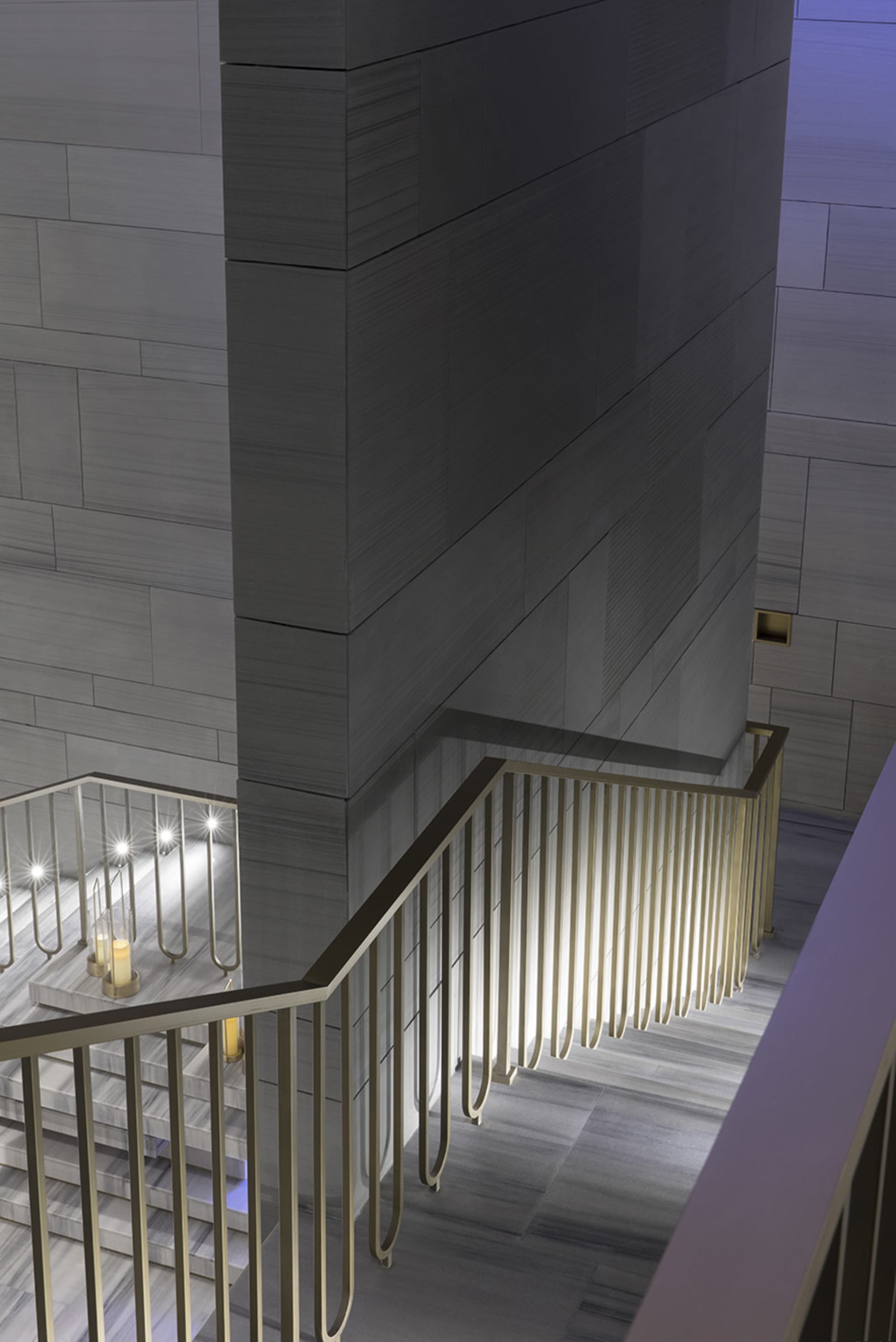 A modern staircase with metal railings and marble steps.
