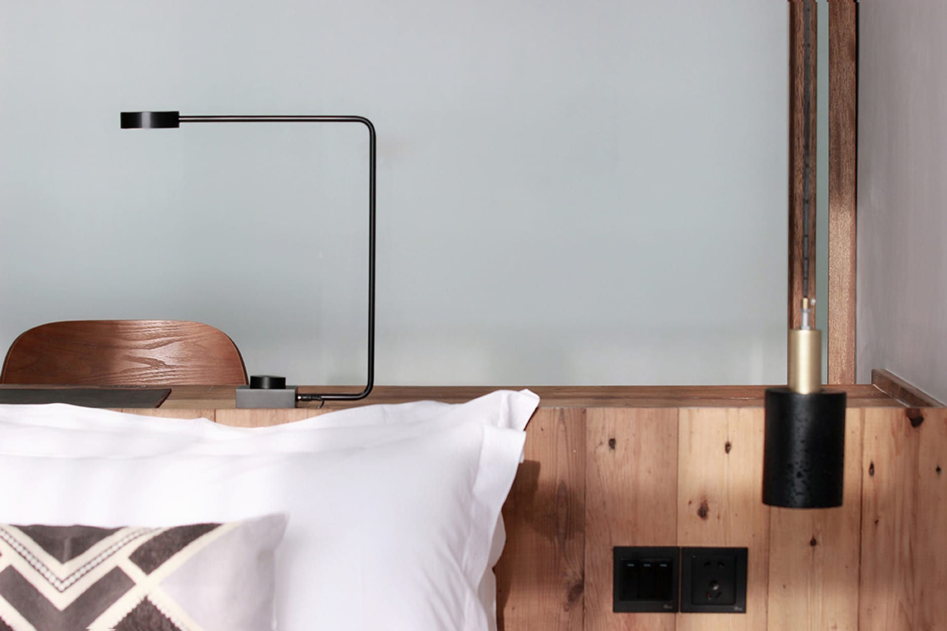 A minimalist bedroom featuring wooden walls and a white pillow.