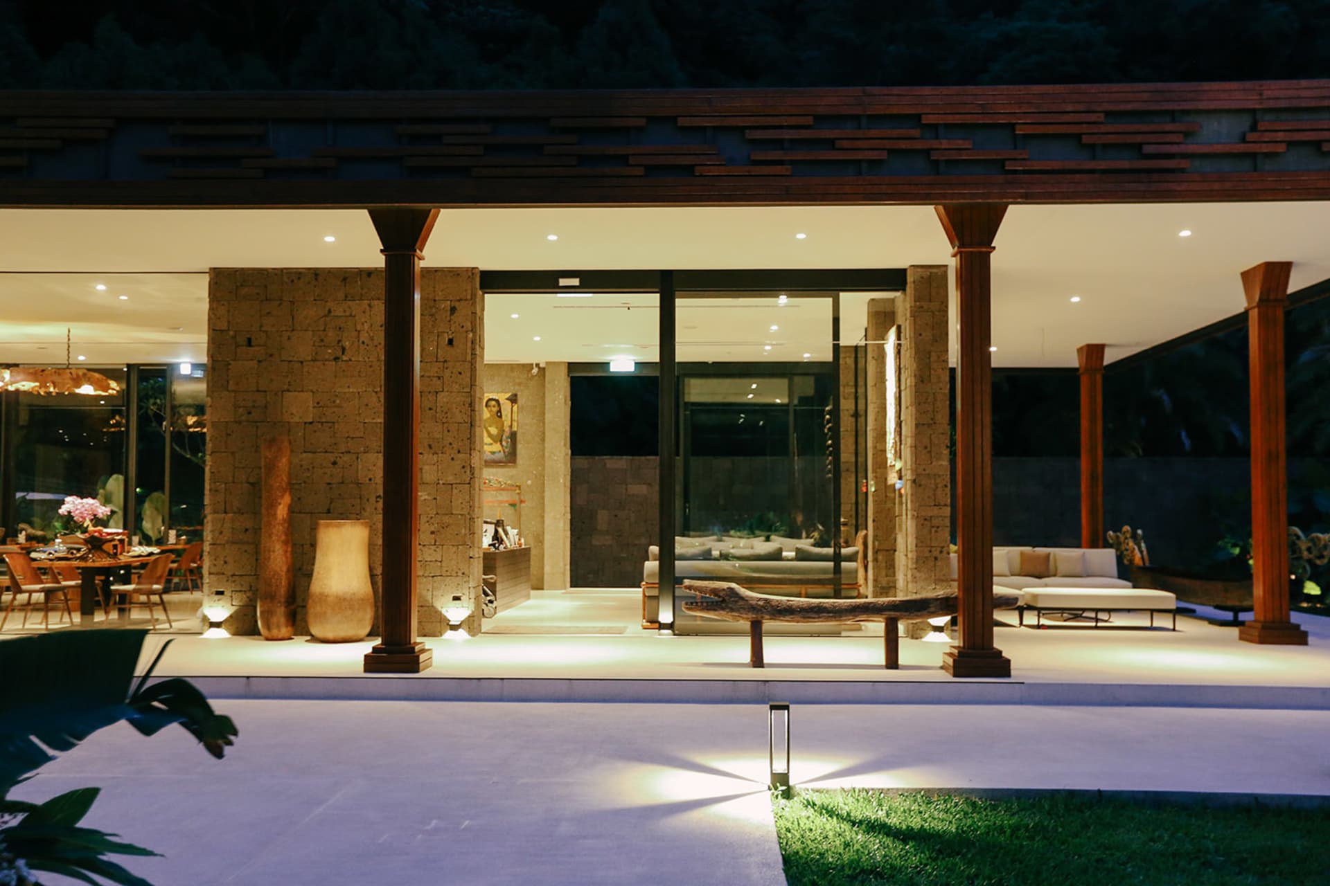 A modern tropical living room featuring stone, glass, and wooden elements.