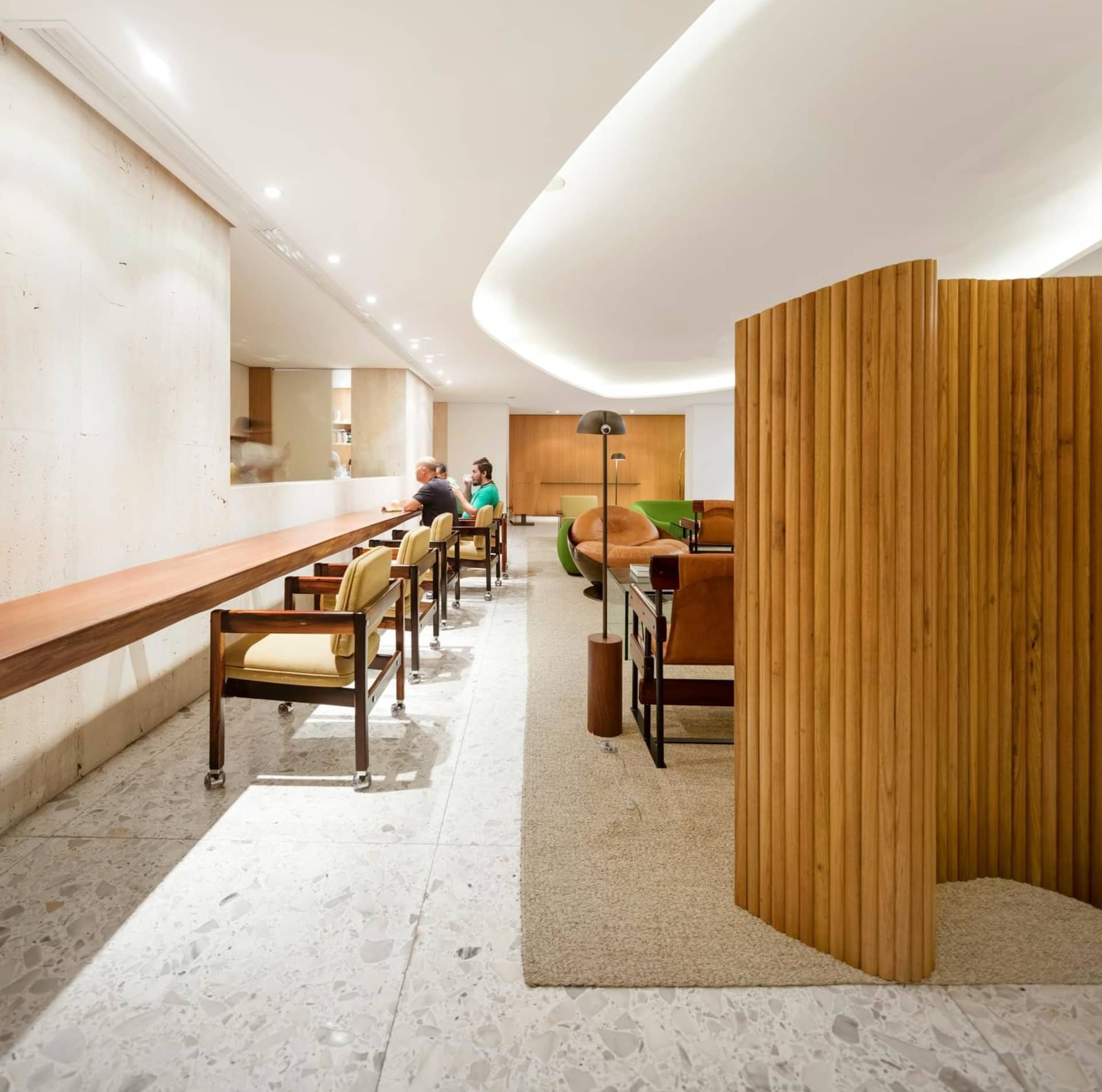 Mid-century modern restaurant lounge with white marble floor, wooden seating, and leather chairs