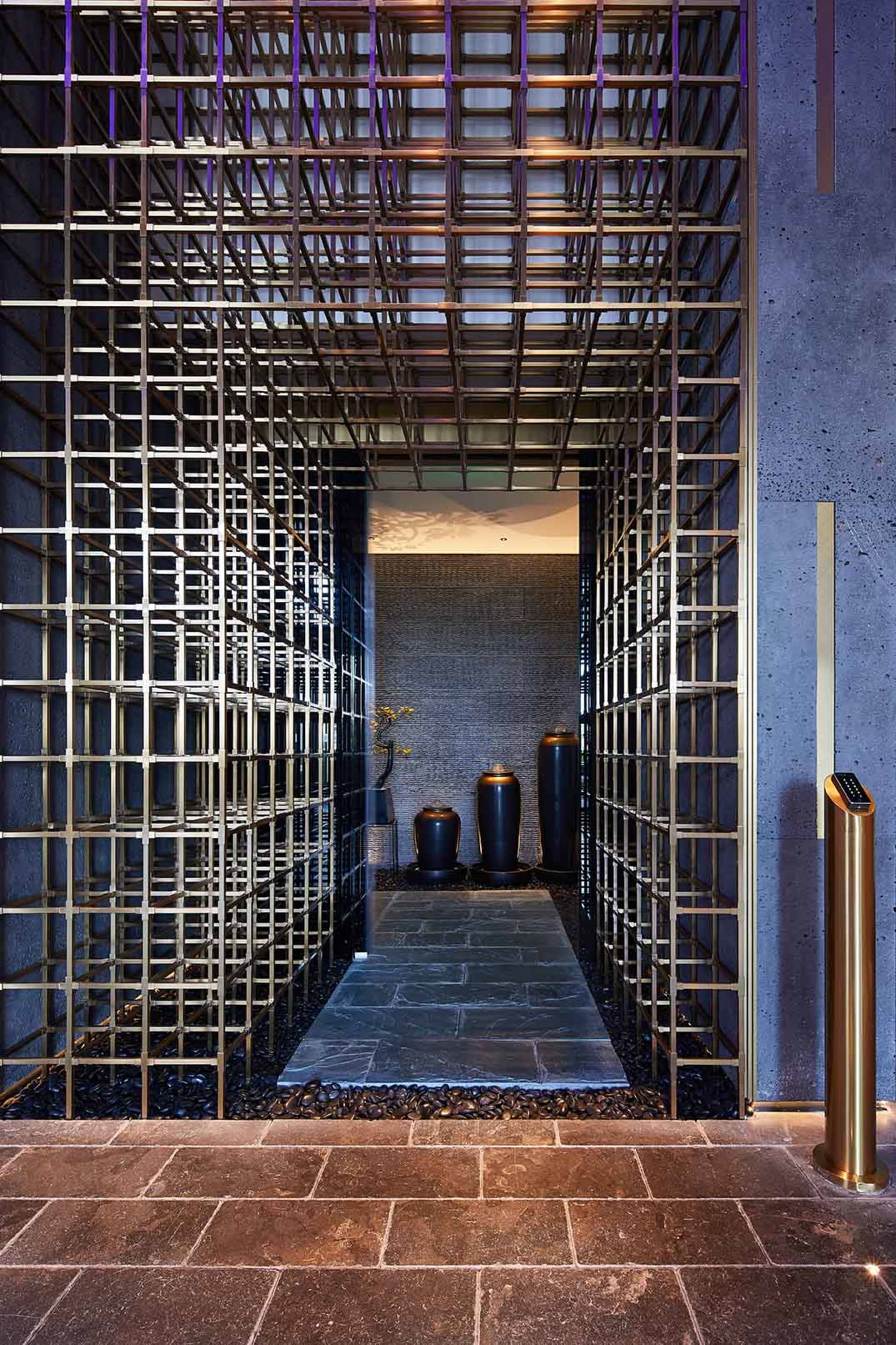 A modern lobby featuring a water feature surrounded by metal railings and stone flooring.