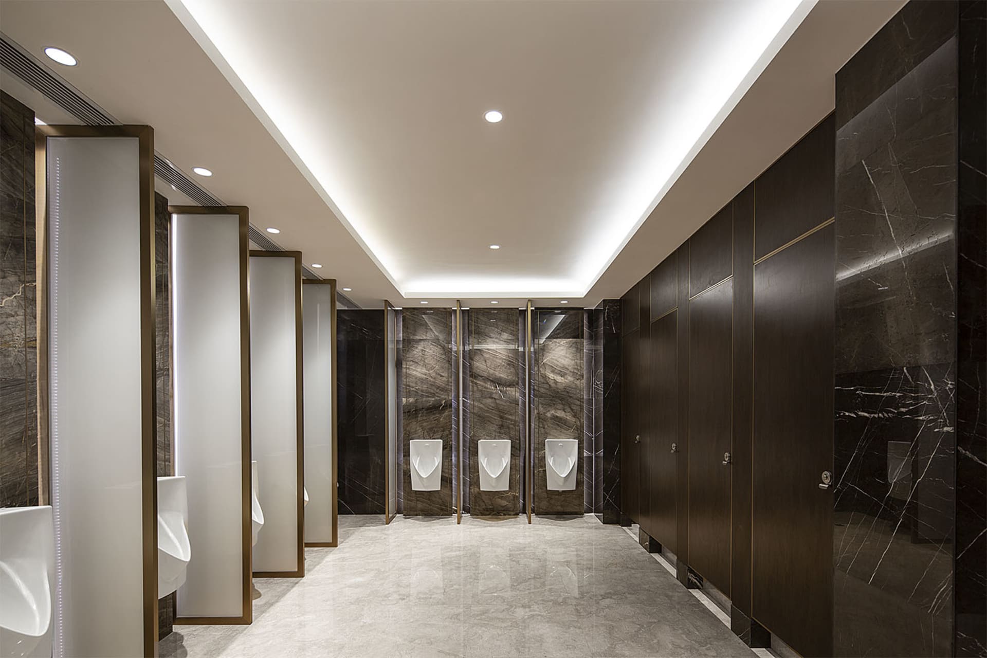 A modern, industrial public bathroom interior with marble walls and wooden partitions.