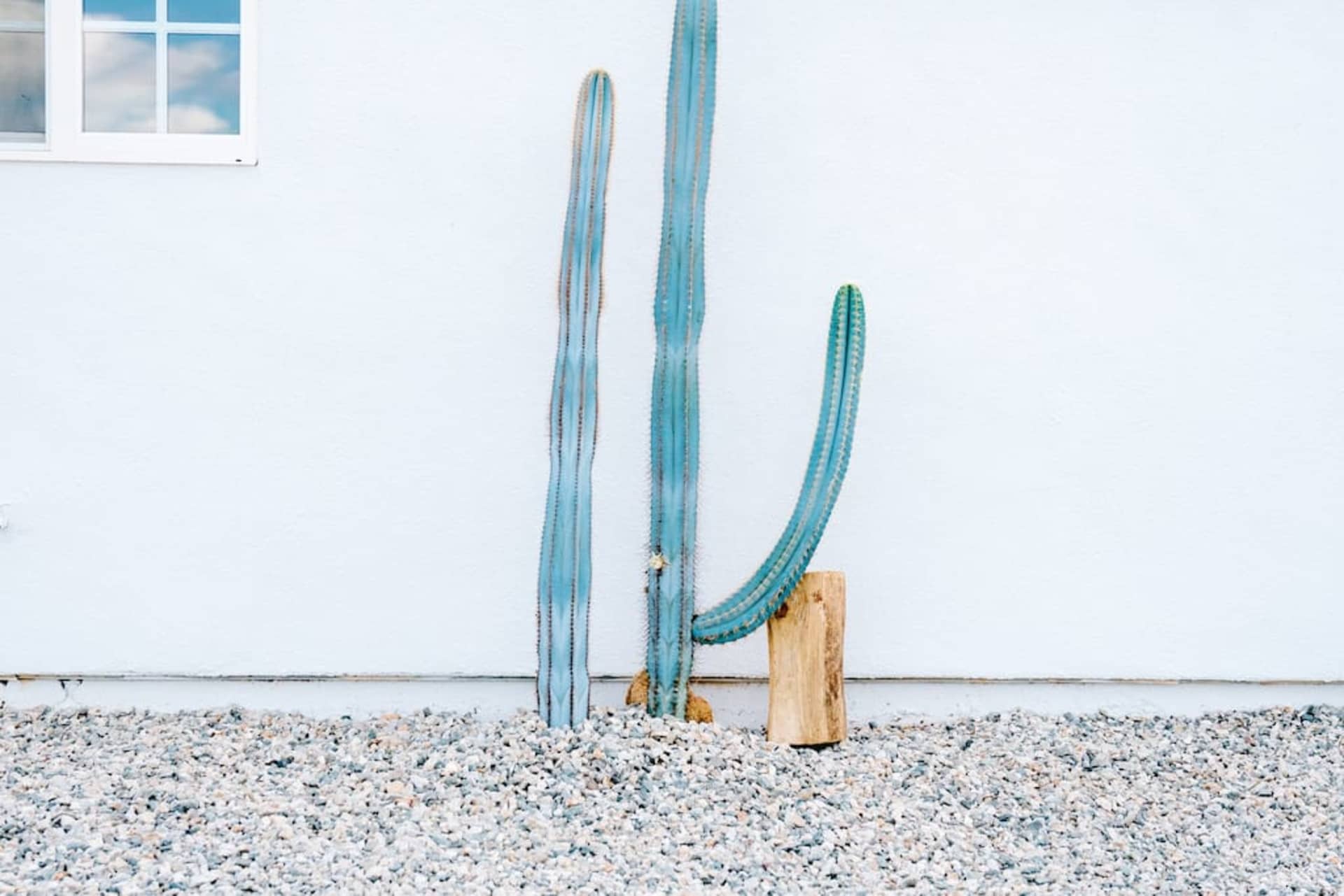 A minimalist landscape featuring a white wall, concrete base, and gravel ground.