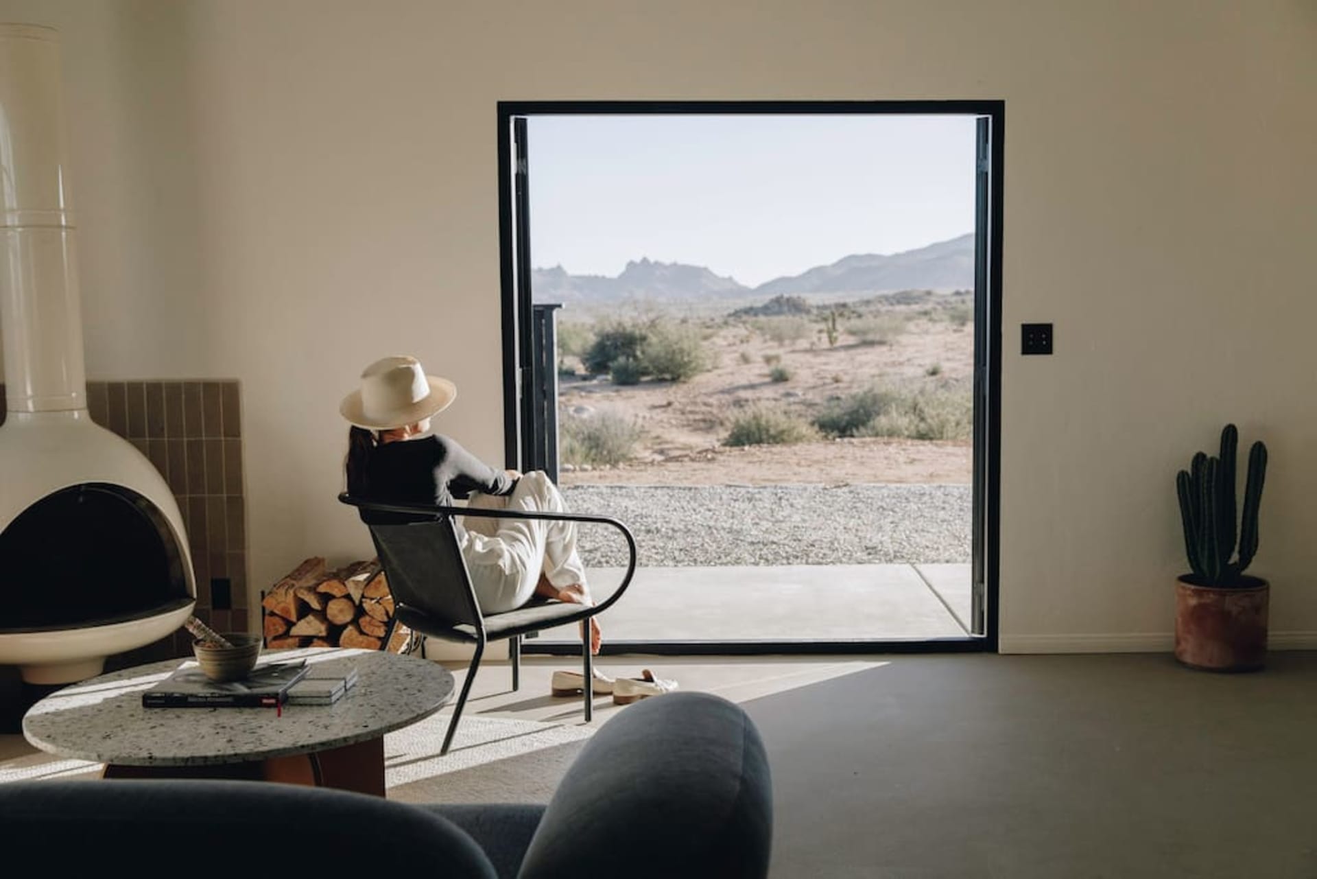 A minimalist living room with a modern terrazzo floor and floor-to-ceiling windows overlooking a desert landscape.