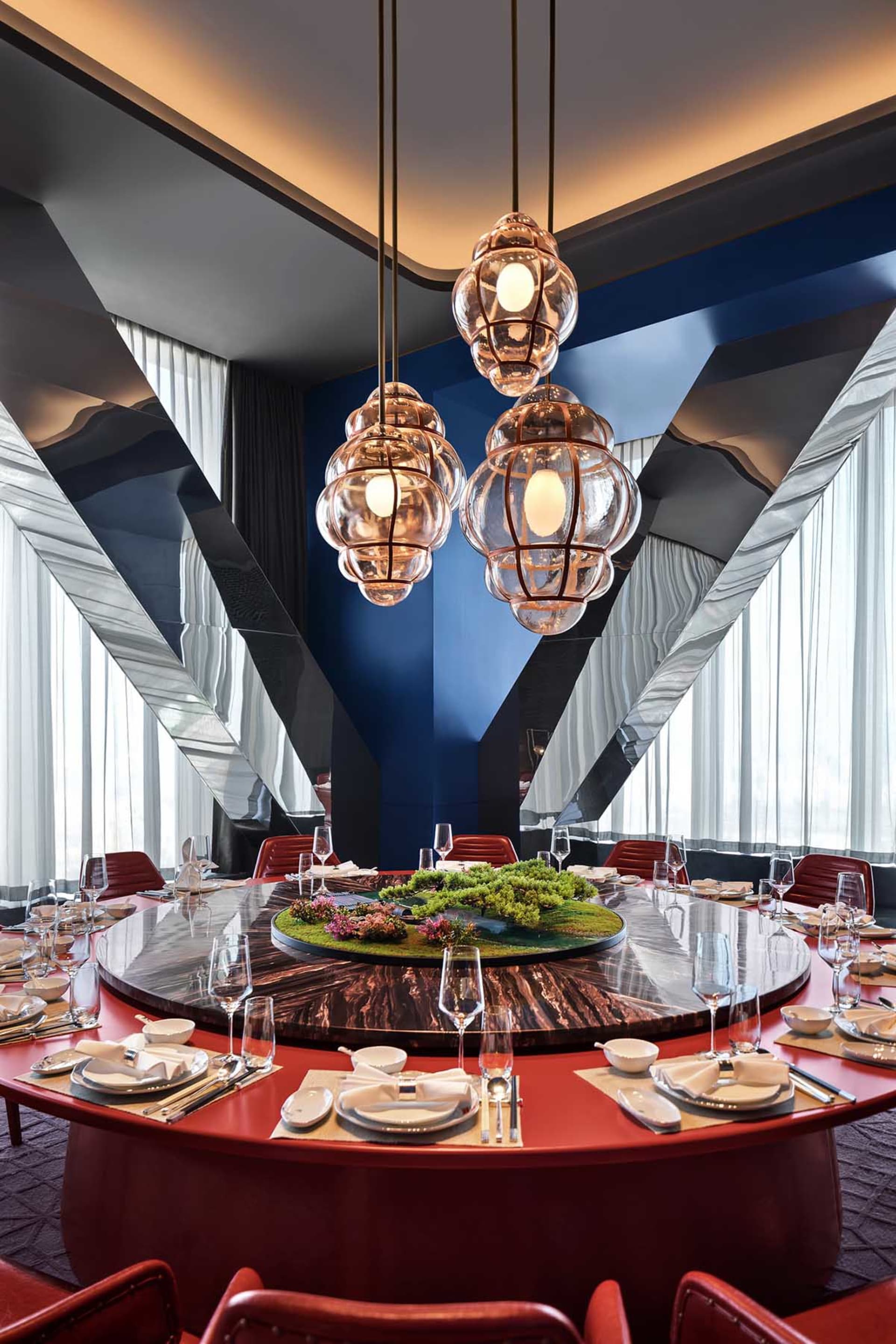 Modern restaurant interior with glass lighting fixtures and a marble dining table.
