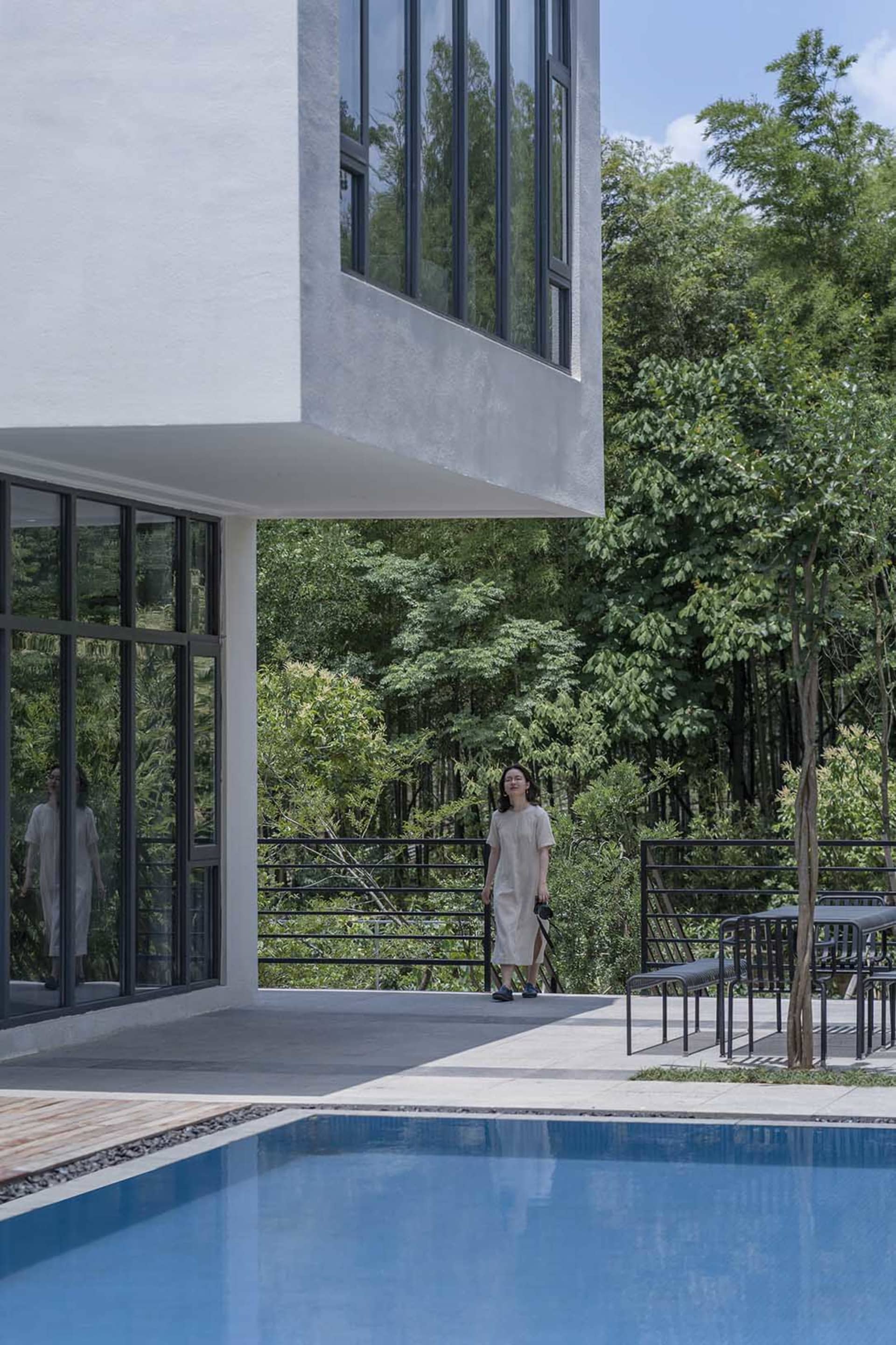 A modern residential home featuring a white concrete exterior and large glass windows.