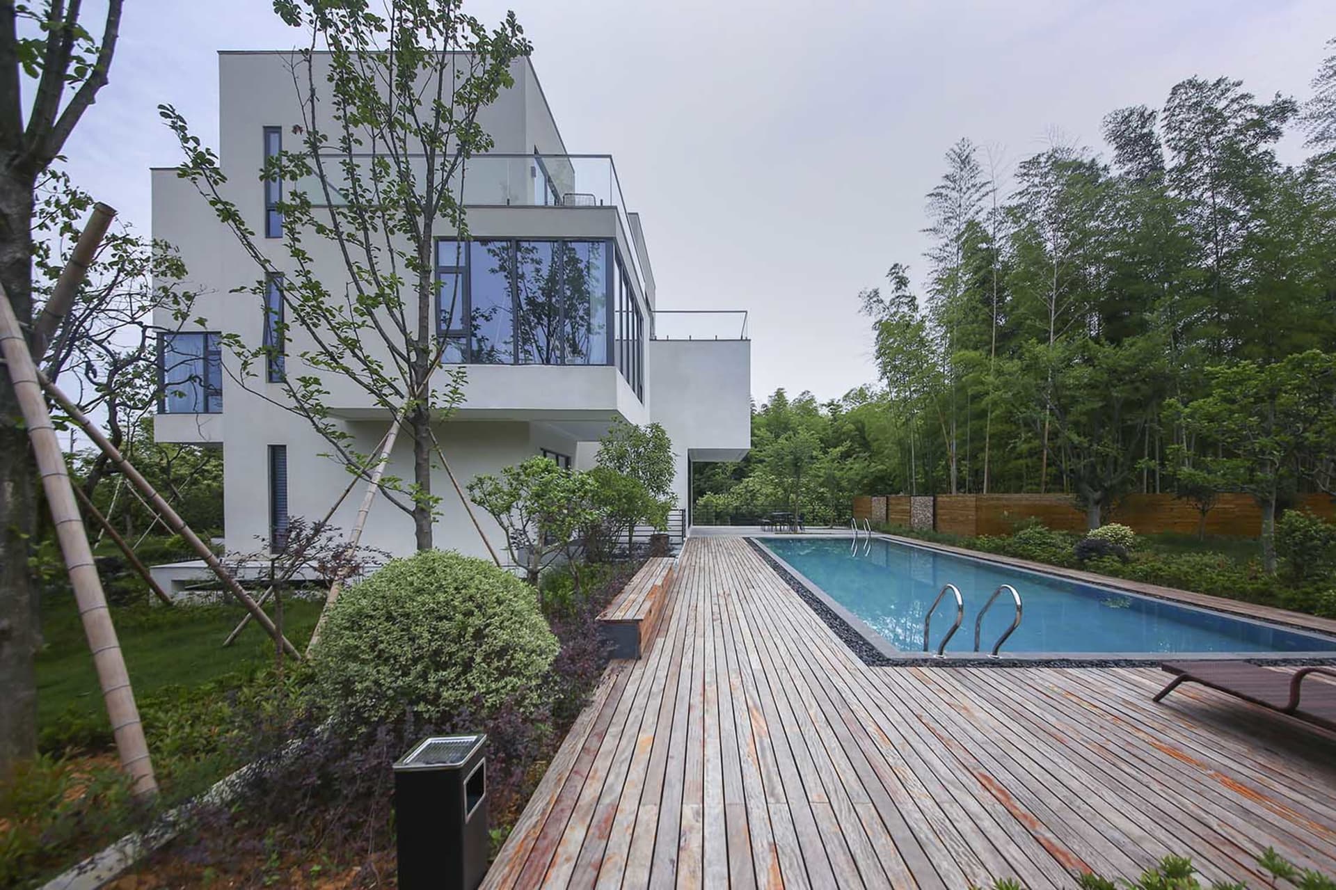 Modern white concrete house exterior with pool and deck.