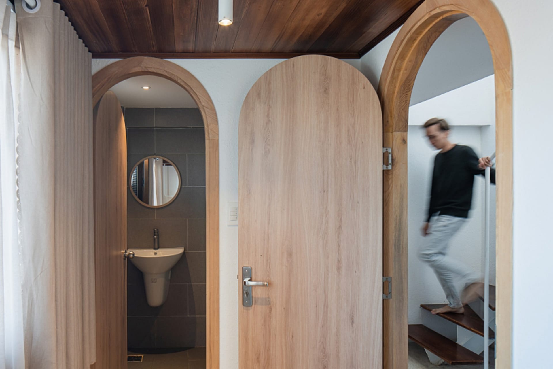 A modern minimalist bathroom with wooden elements and a sink in the background.
