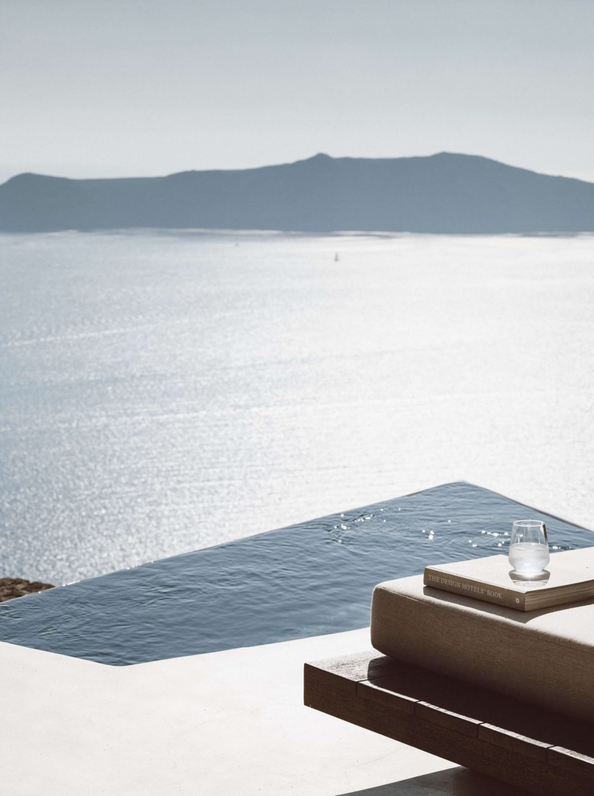 A minimalist holiday villa with a concrete structure and a view of the serene sea.