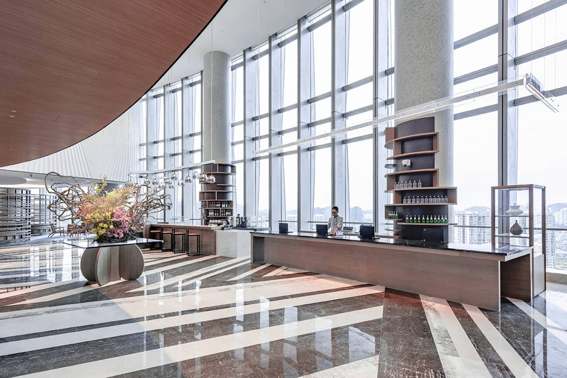 A modern hotel lobby featuring glass, wood, and marble materials.