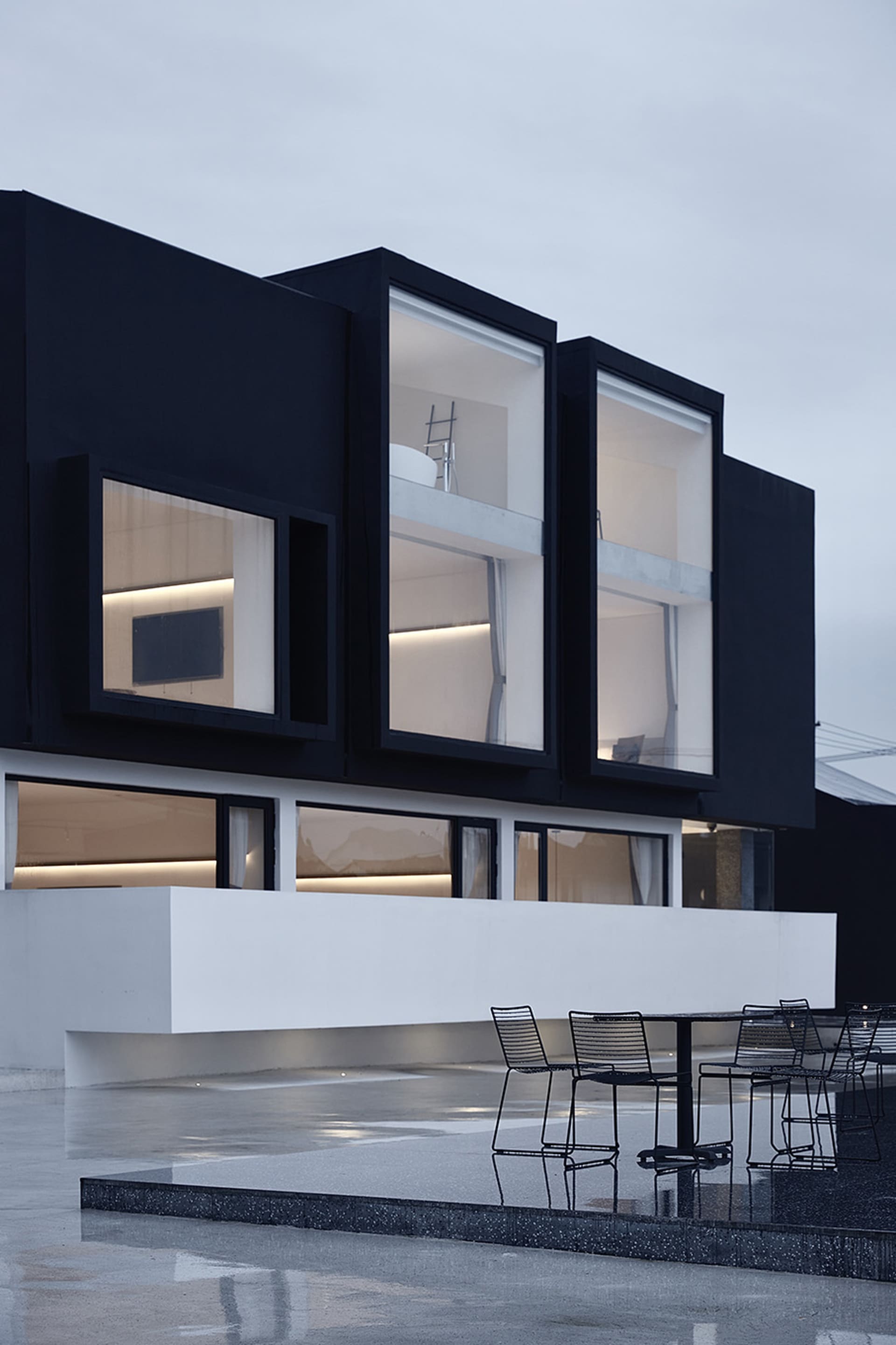 A modern house with large glass windows and a black exterior.