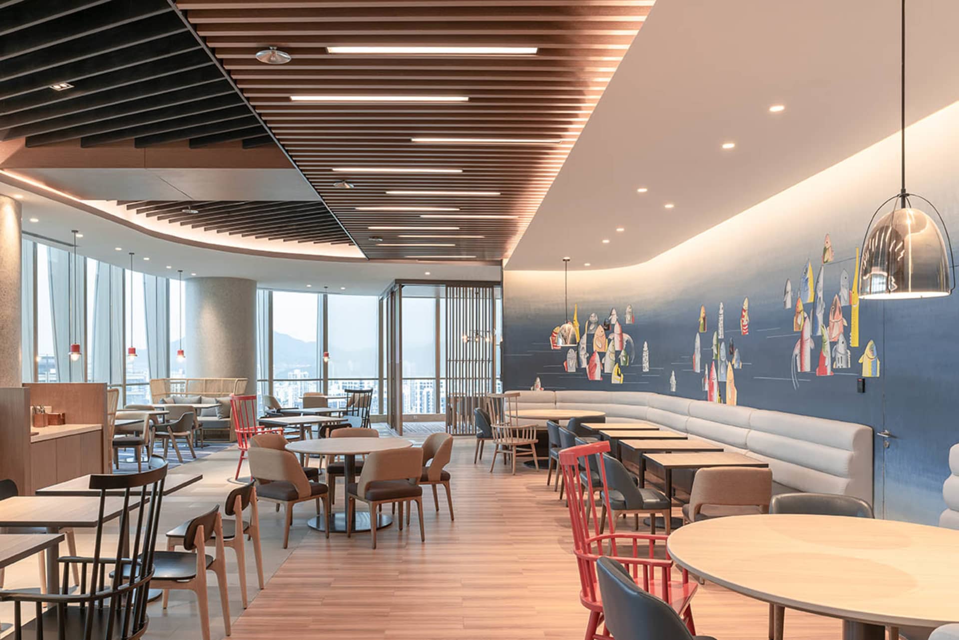 A modern cafe interior with wooden flooring, metallic pendant lights, and upholstered seating.