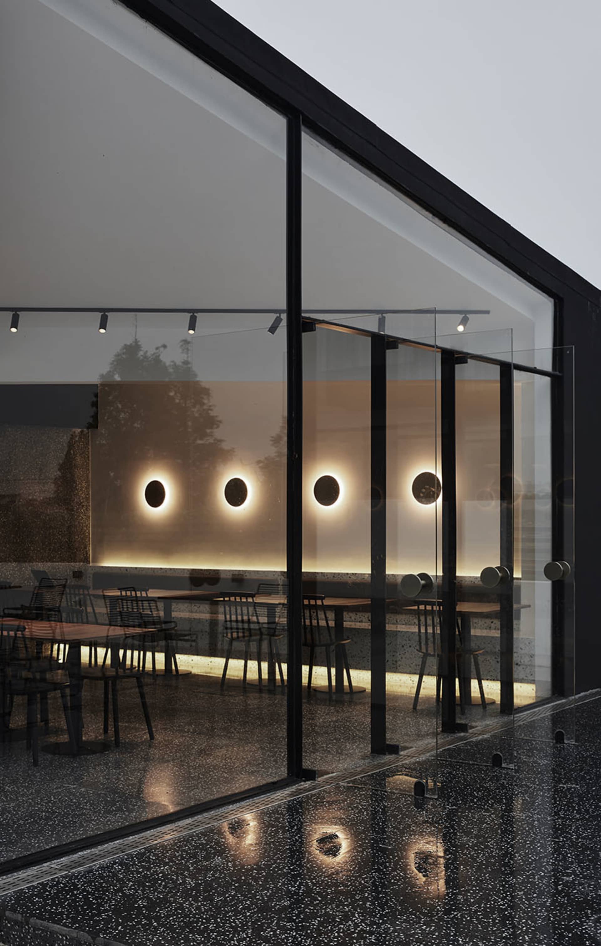 A modern coffee shop featuring glass walls and concrete flooring.