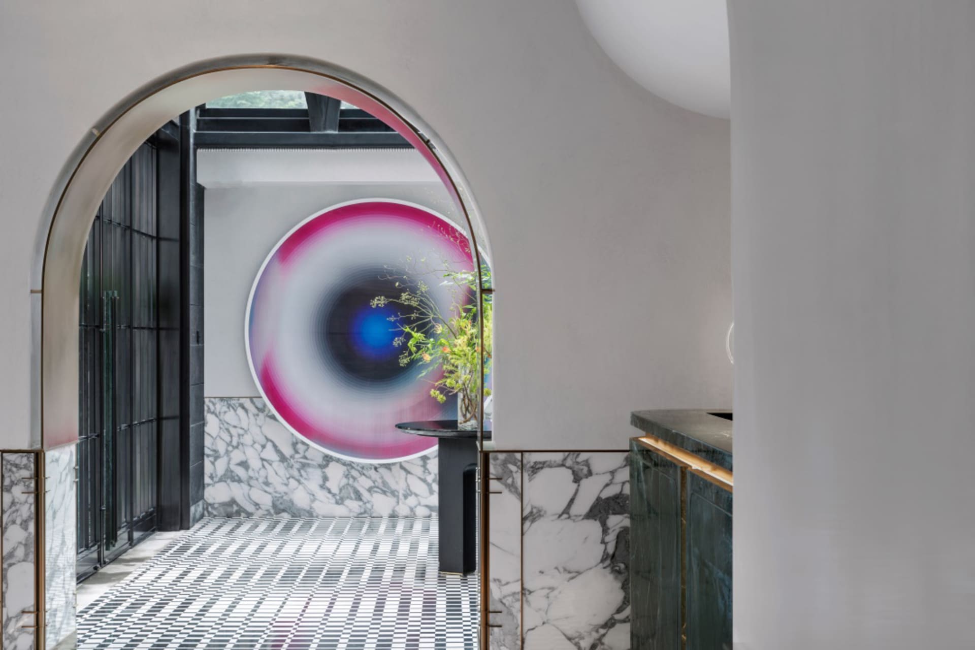 Architectural entrance with modern design featuring marble, concrete, and glass patterns under a large circular artwork.