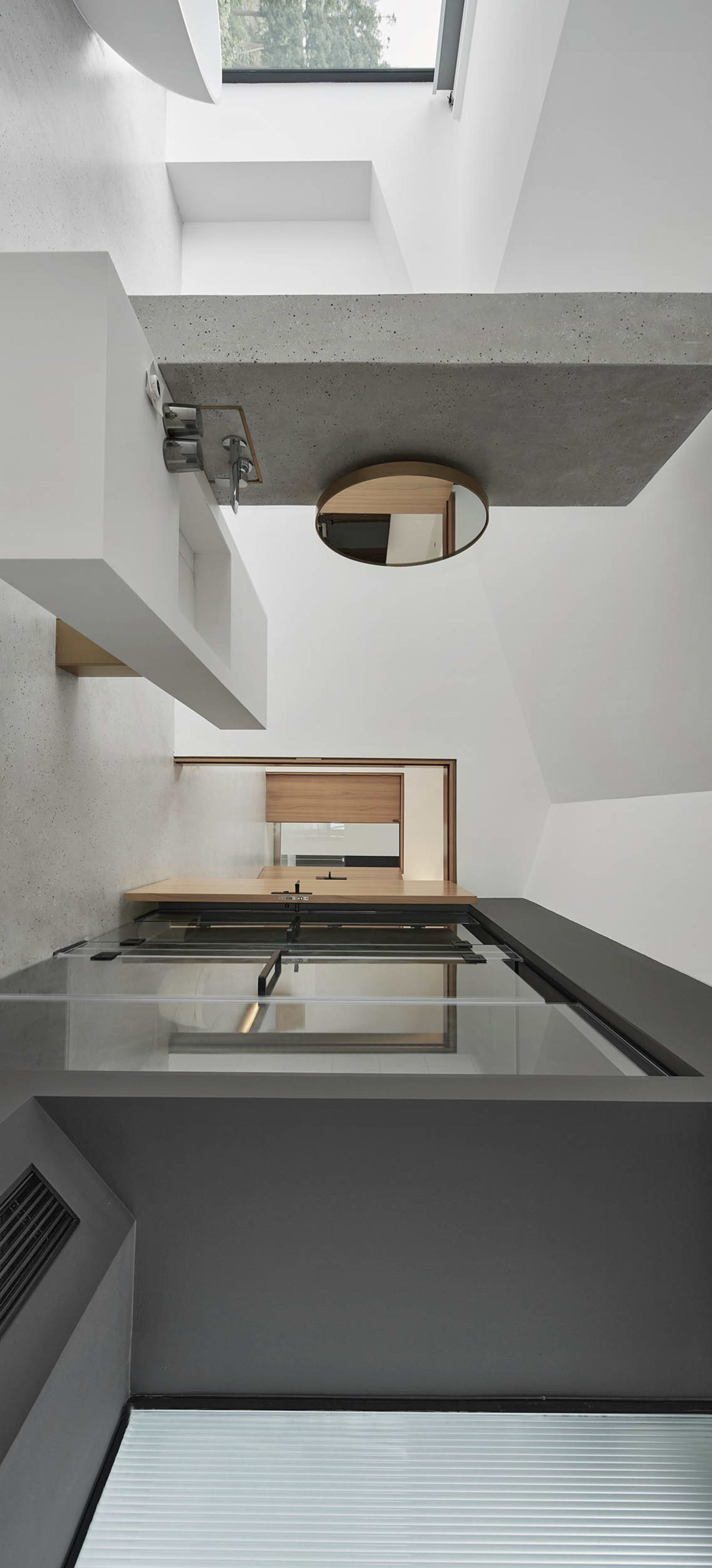 A modern interior space with a minimalist design, featuring concrete walls and a glass floor.