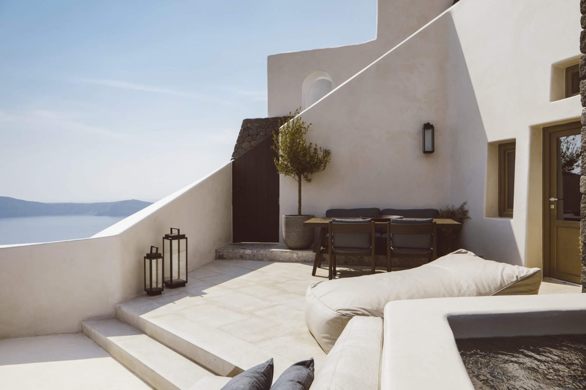 Modern residential patio featuring a concrete floor, stone walls, a dining area with chairs and a table, and a view of the oc