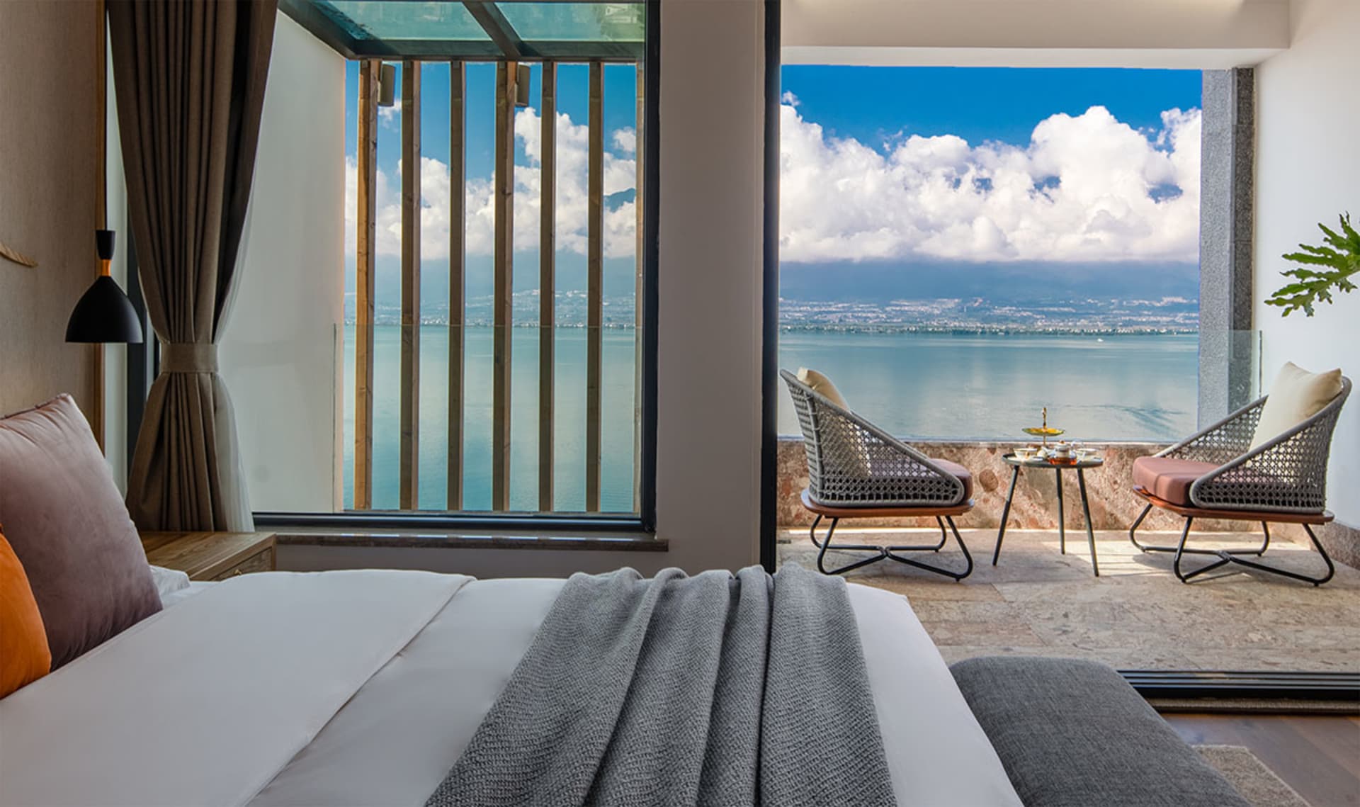 Modern bedroom with a seaview balcony, featuring minimalist furniture and a comfortable bed.