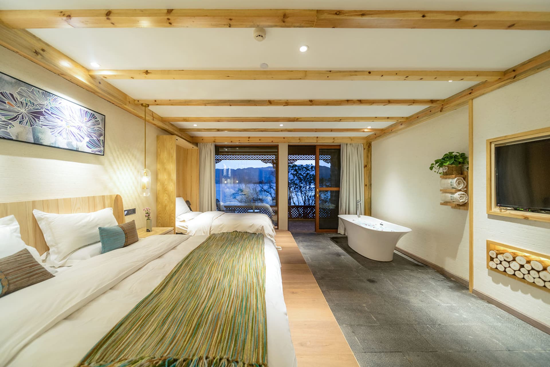 Modern industrial-style hotel room with wood and stone accents, featuring a minimalistic decor and a bathtub area with a scen