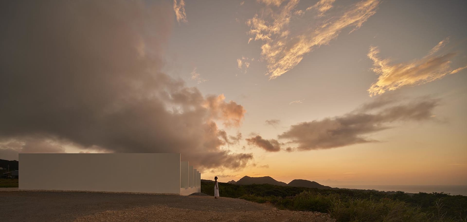 A serene outdoor scene with a cloudy sky and person standing near a building.