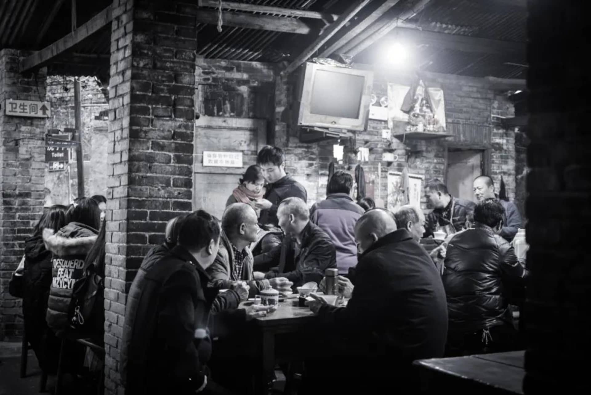 A bustling street food restaurant adorned with rustic brick and concrete walls, featuring patrons dining at tables.