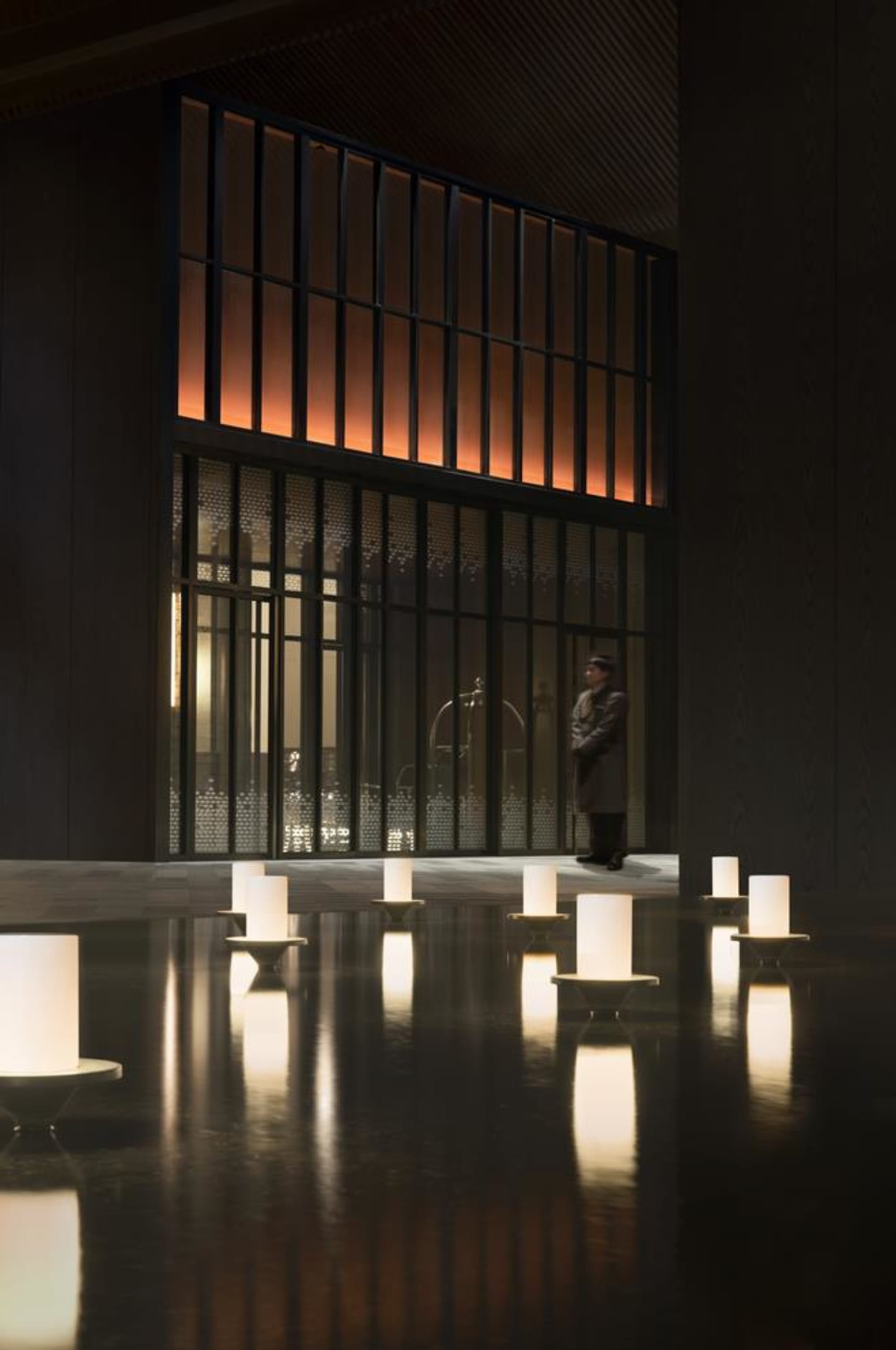 A minimalist lobby featuring dark wood, glass, and concrete materials