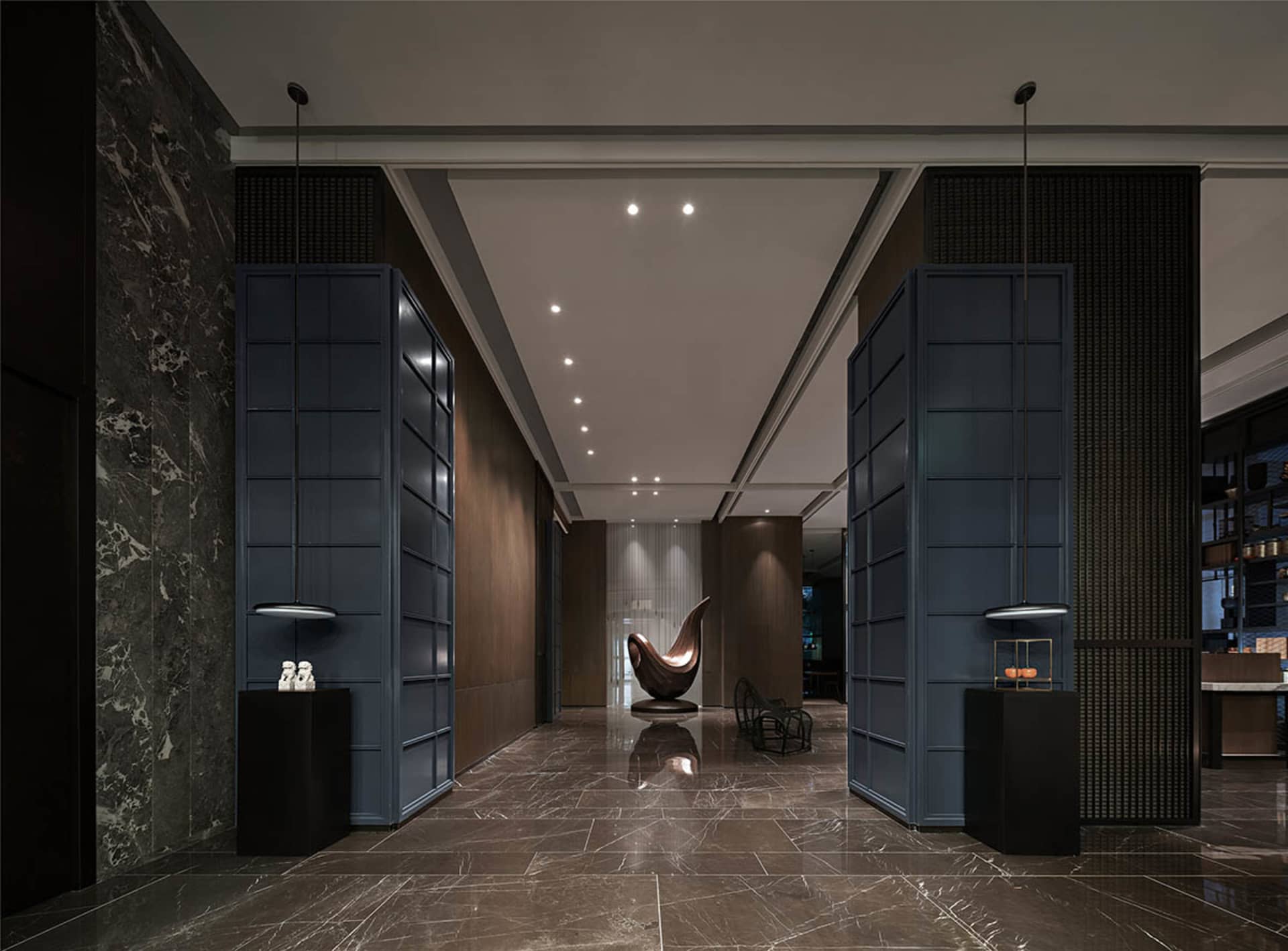 A modern minimalist lobby with a sleek metal chair, marble floor, and glass elements.