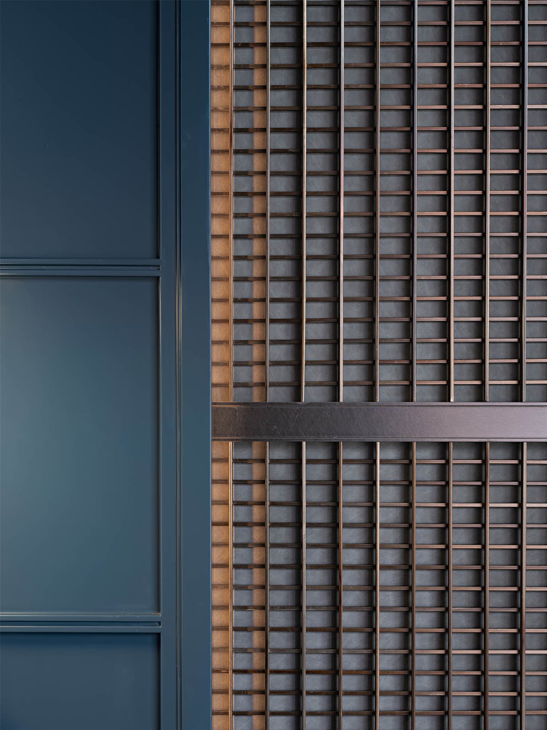 A section of wall featuring a minimalist design with vertical metal bars and horizontal leather belts.