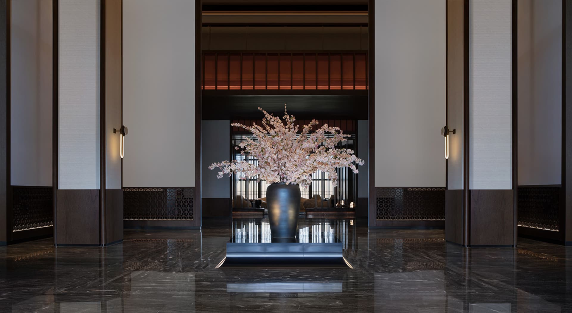 Modern hotel lobby with a marble floor and black vase with pink flowers.