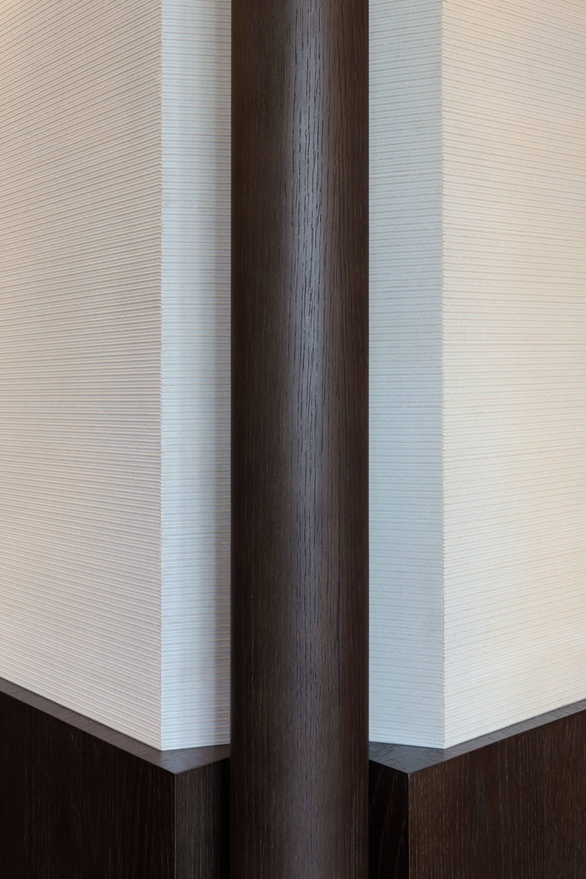 A close-up view of a modern interior design featuring dark wood-paneled walls with a textured surface.