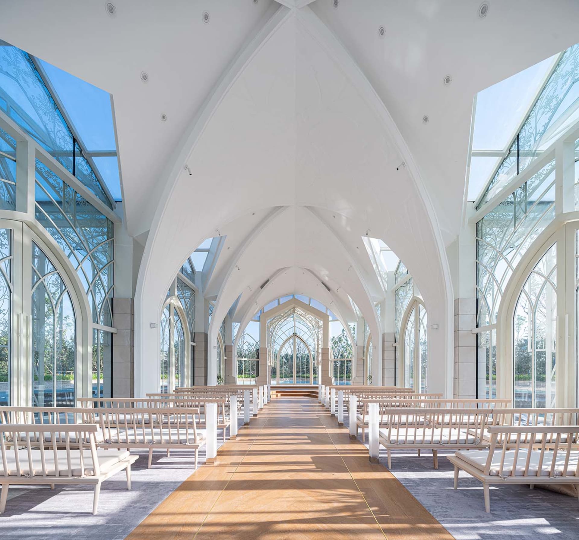 Modern church interior with glass walls, wooden benches, and concrete structural elements.