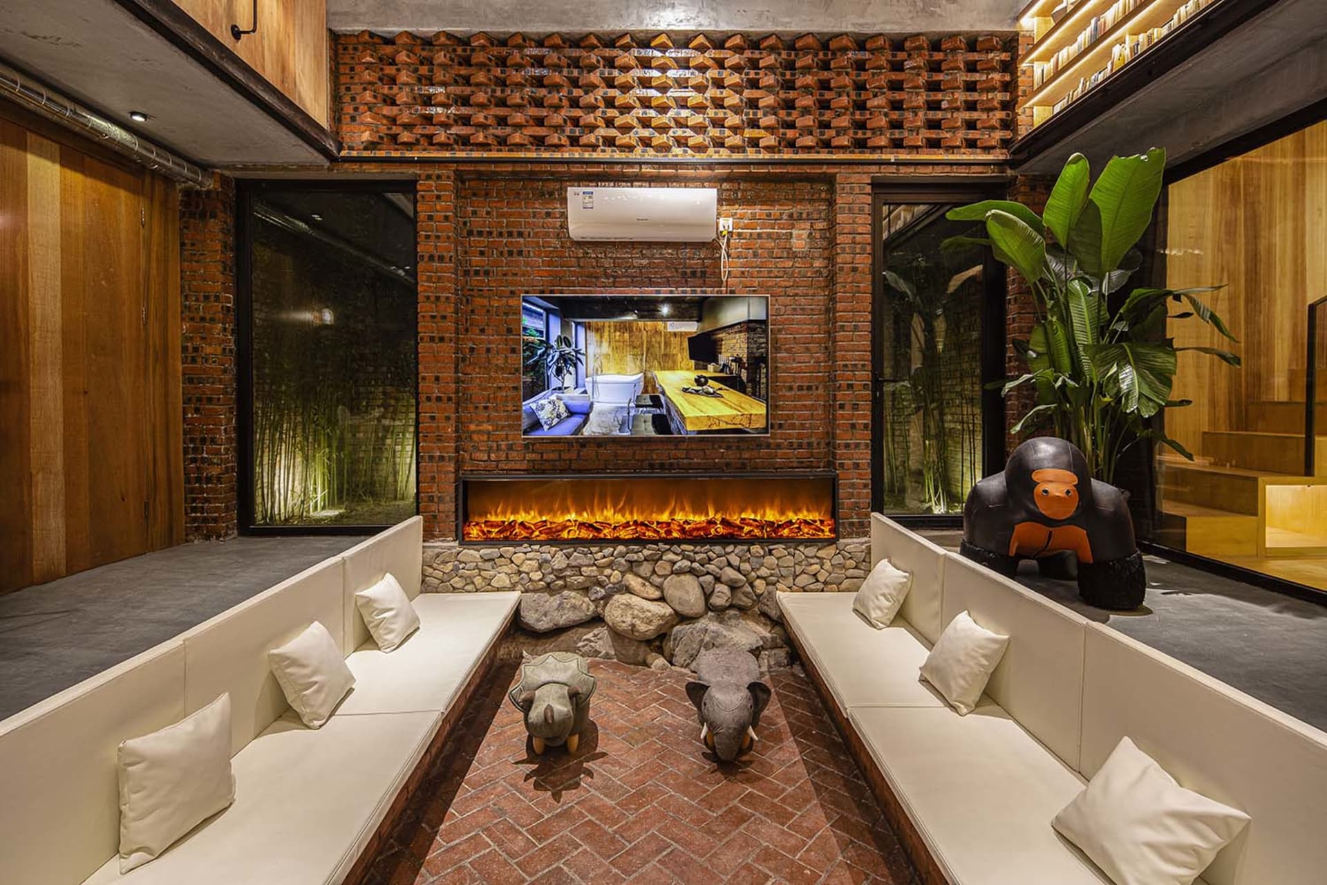 A cozy industrial-style living room with brick walls, a fireplace, and comfortable seating.