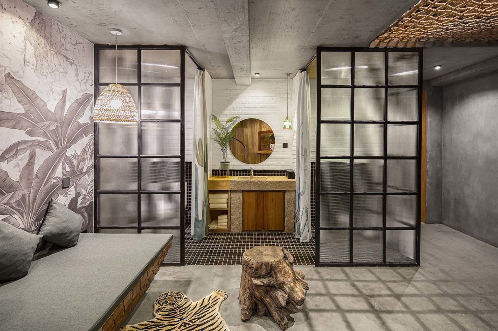 A modern industrial hotel suite featuring a concrete floor with a grid pattern, natural wood accents, and furniture designed