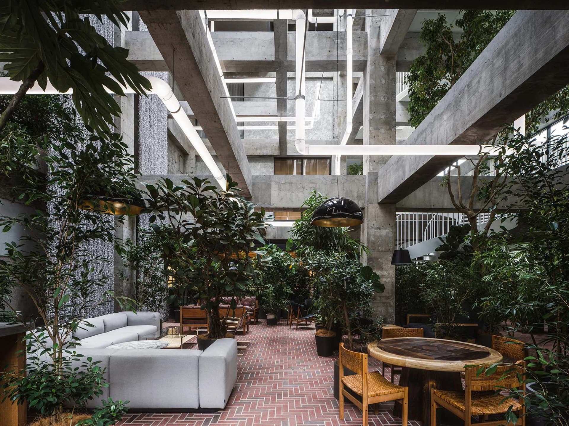 Industrial office space with concrete walls, open-air ceiling, and greenery.