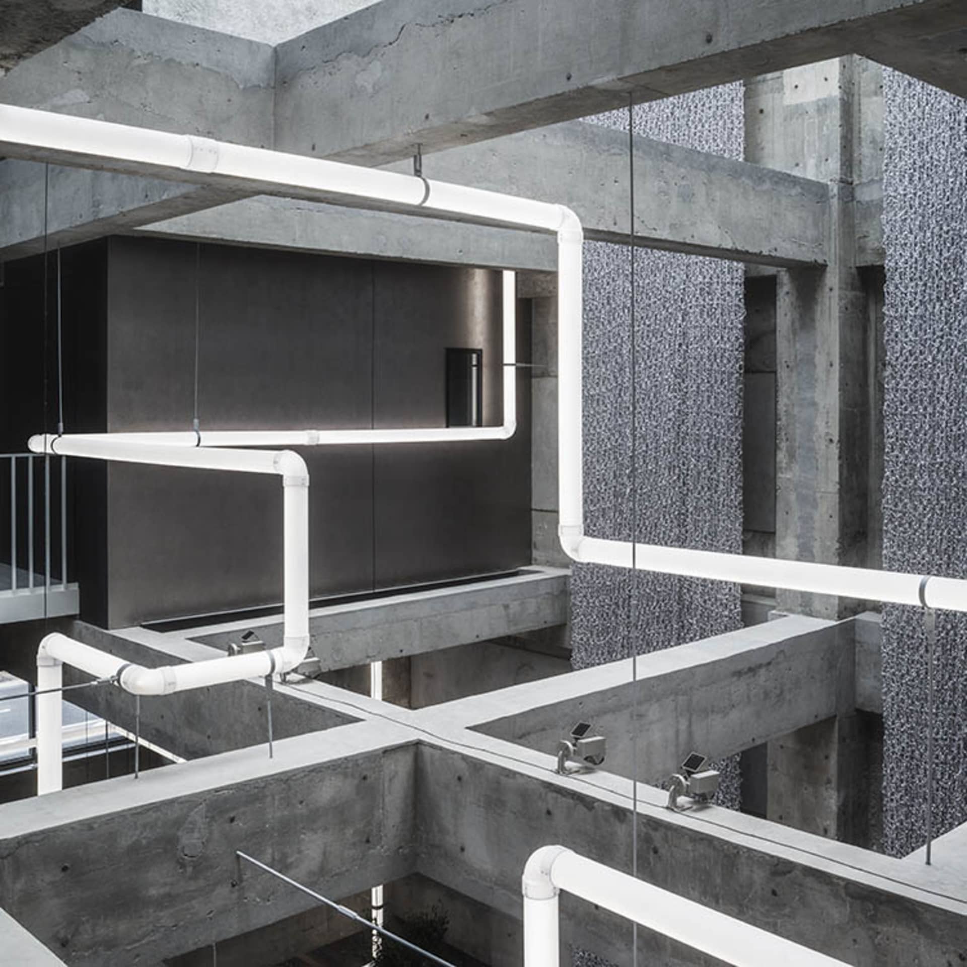 Modern interior space featuring concrete pipes and minimalist design elements.