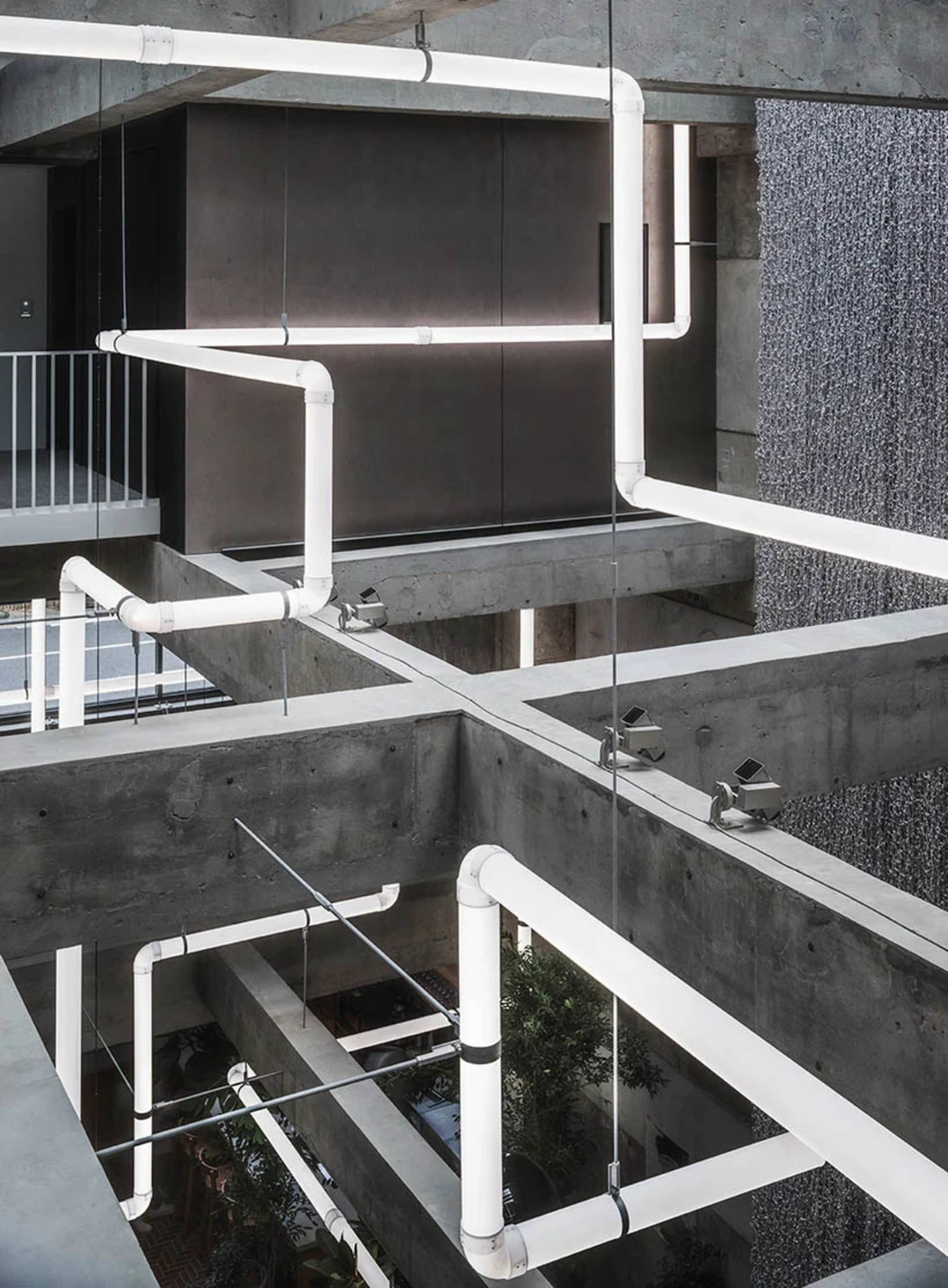 A modern industrial office space featuring exposed concrete pipes and minimalist design elements.