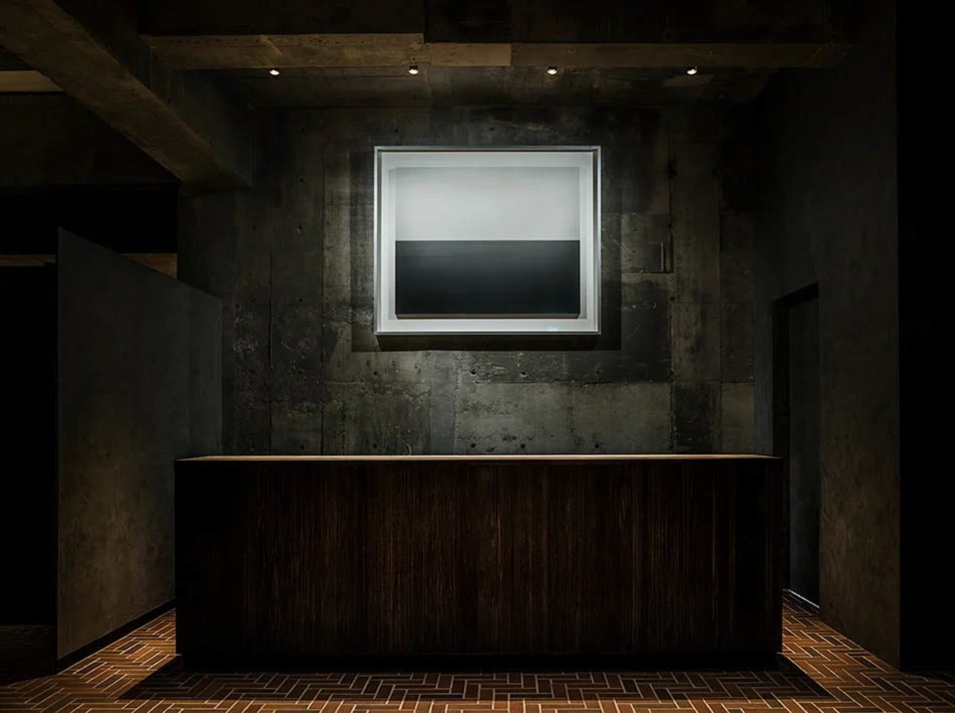 A minimalist lobby featuring industrial-style concrete and wood materials.