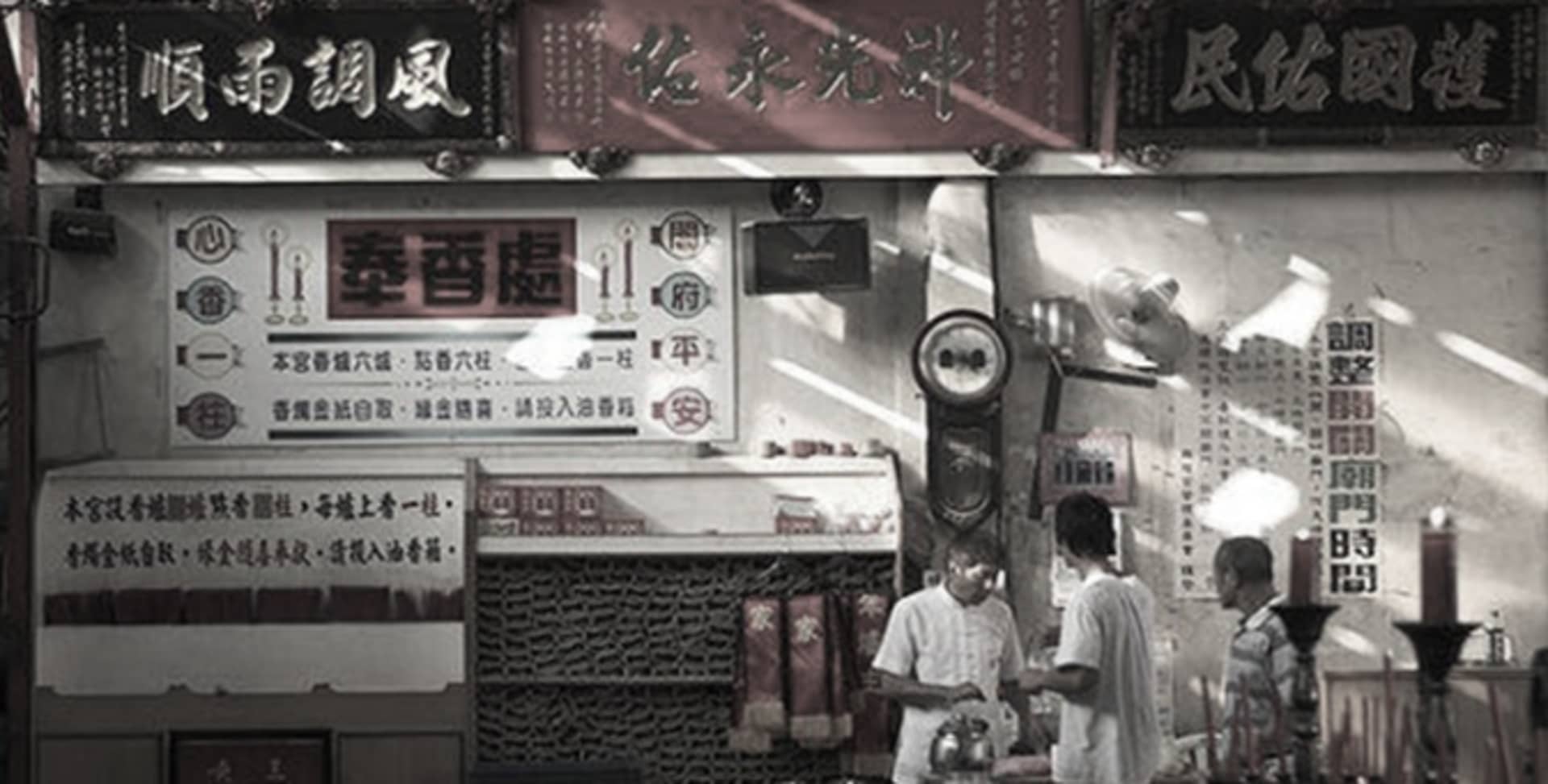 A group of people standing in front of a Chinese altar temple with various signs written in Chinese characters and metal stru