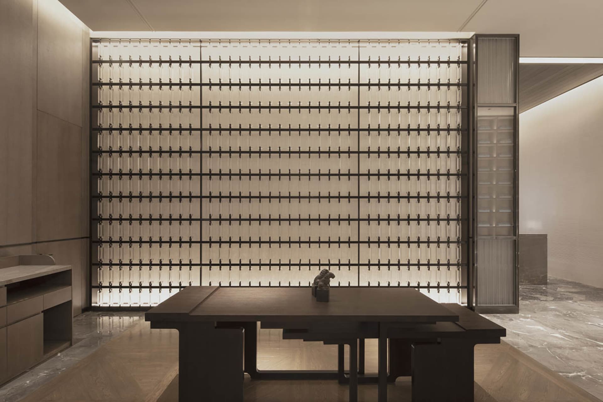 Modern hotel lobby featuring glass wall panels and minimalist furniture.