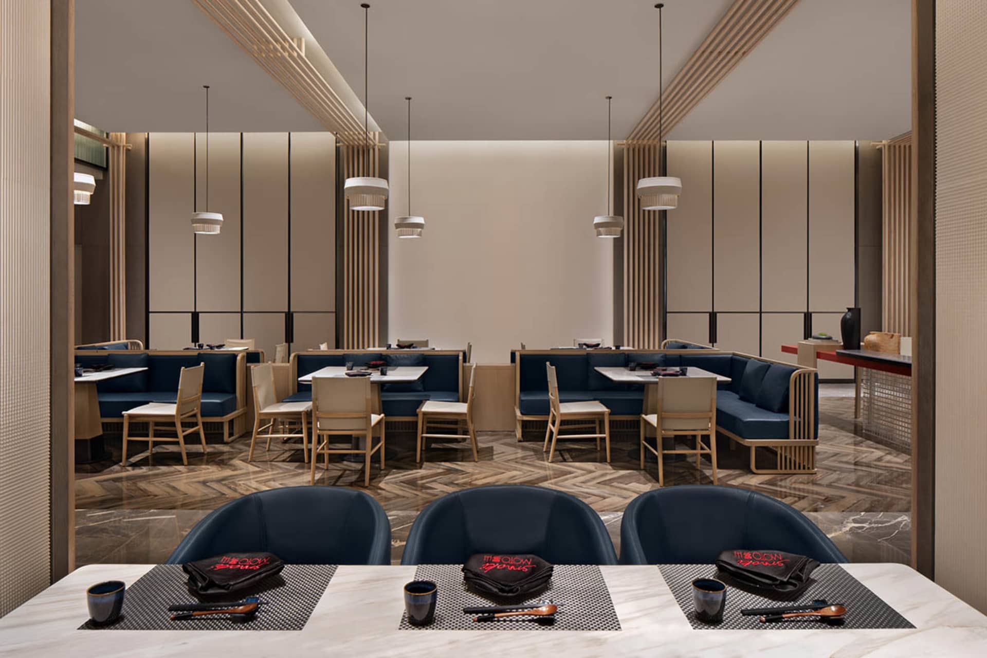 Modern restaurant interior with blue seating and wooden finishes.