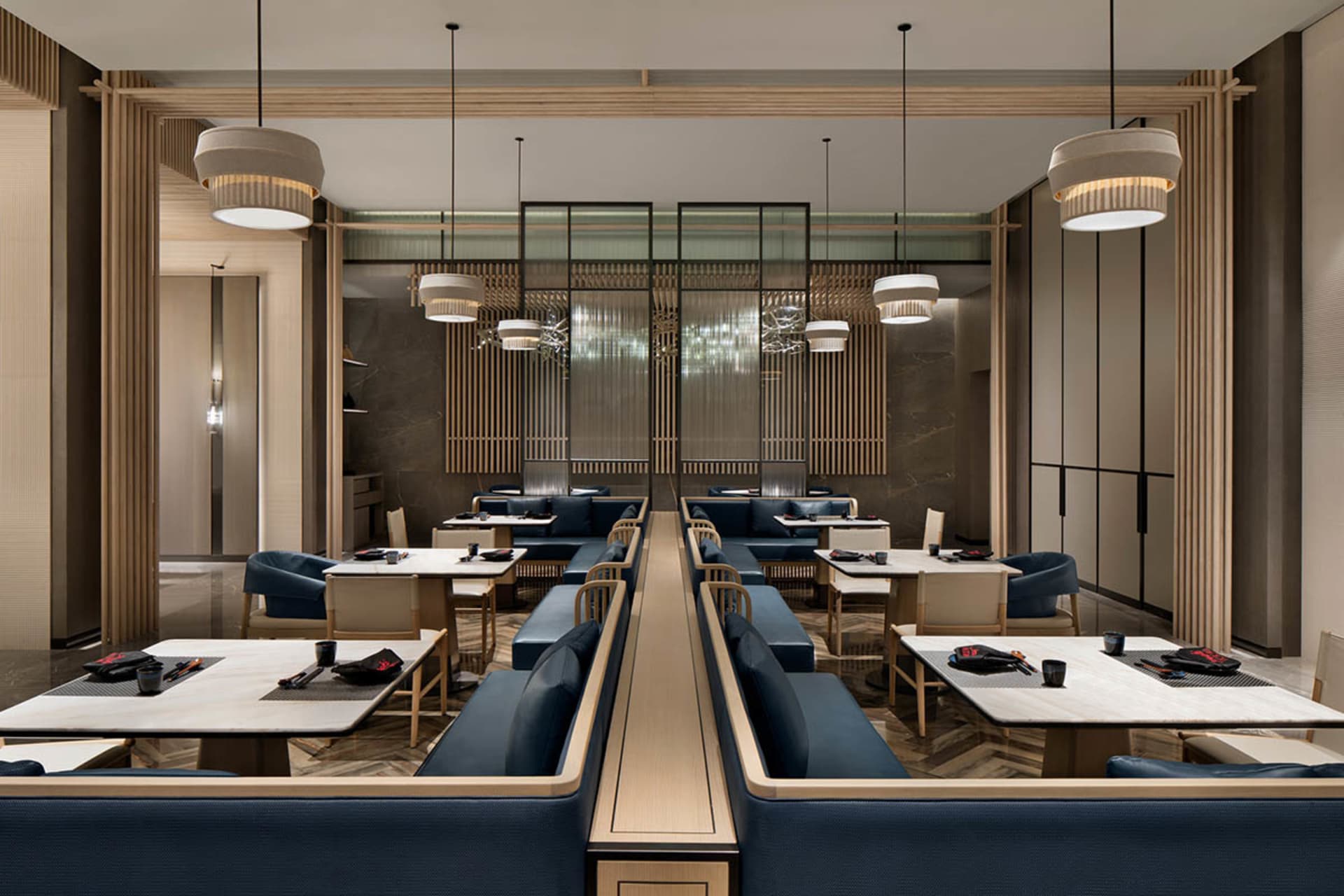Modern restaurant interior with wooden tables, marble countertops, and metal accents.