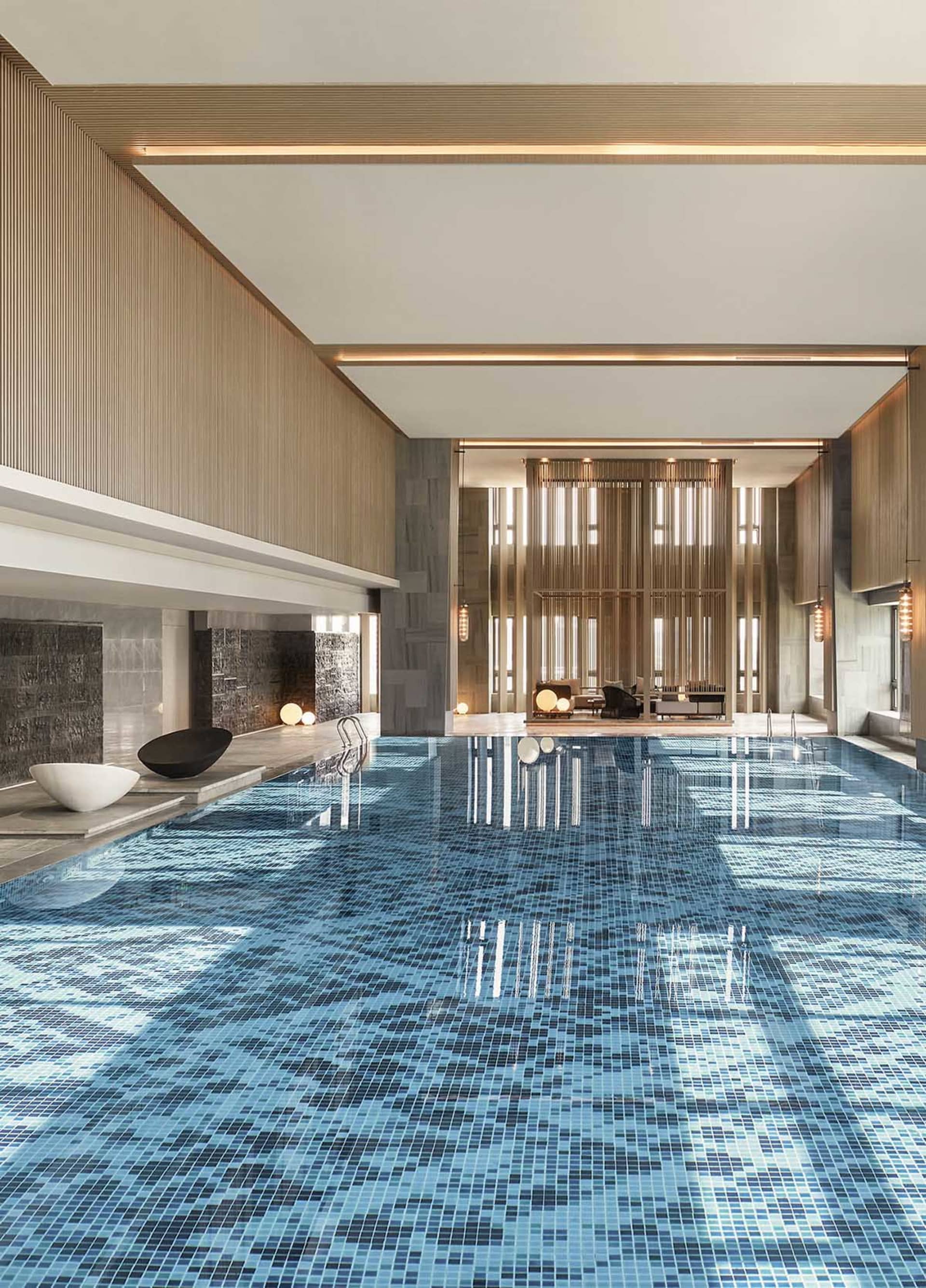 Modern indoor swimming pool with glass-tiled floor and wooden panelling