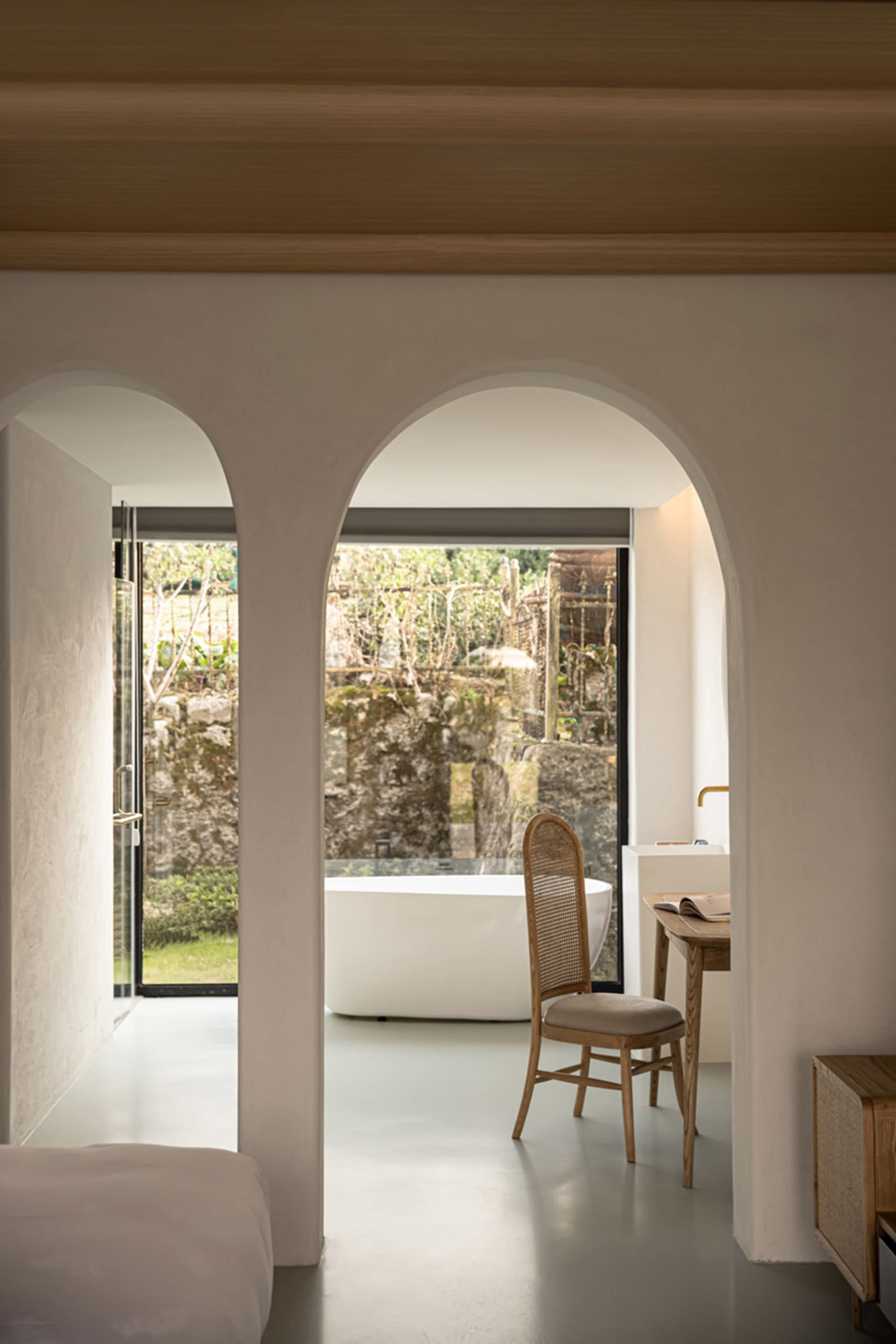 A minimalist bathroom with a white marble floor, walls, and bathtub.