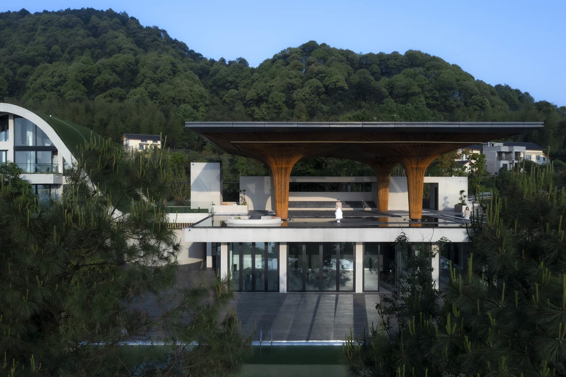 A modern architectural building featuring a wooden facade, concrete base, and glass roof.